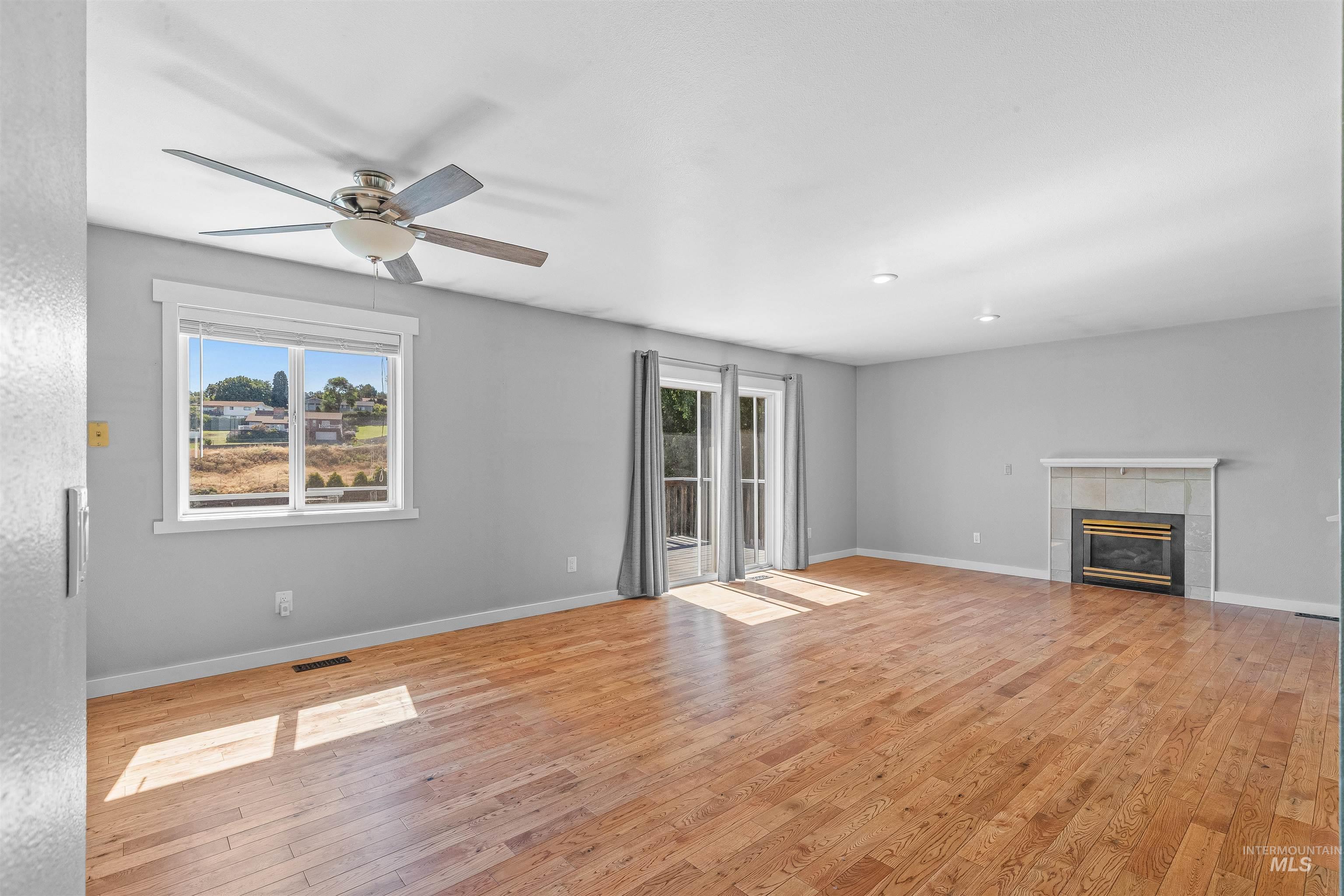 Unfurnished living room featuring ceiling fan, light wood-style floors, and a fireplace