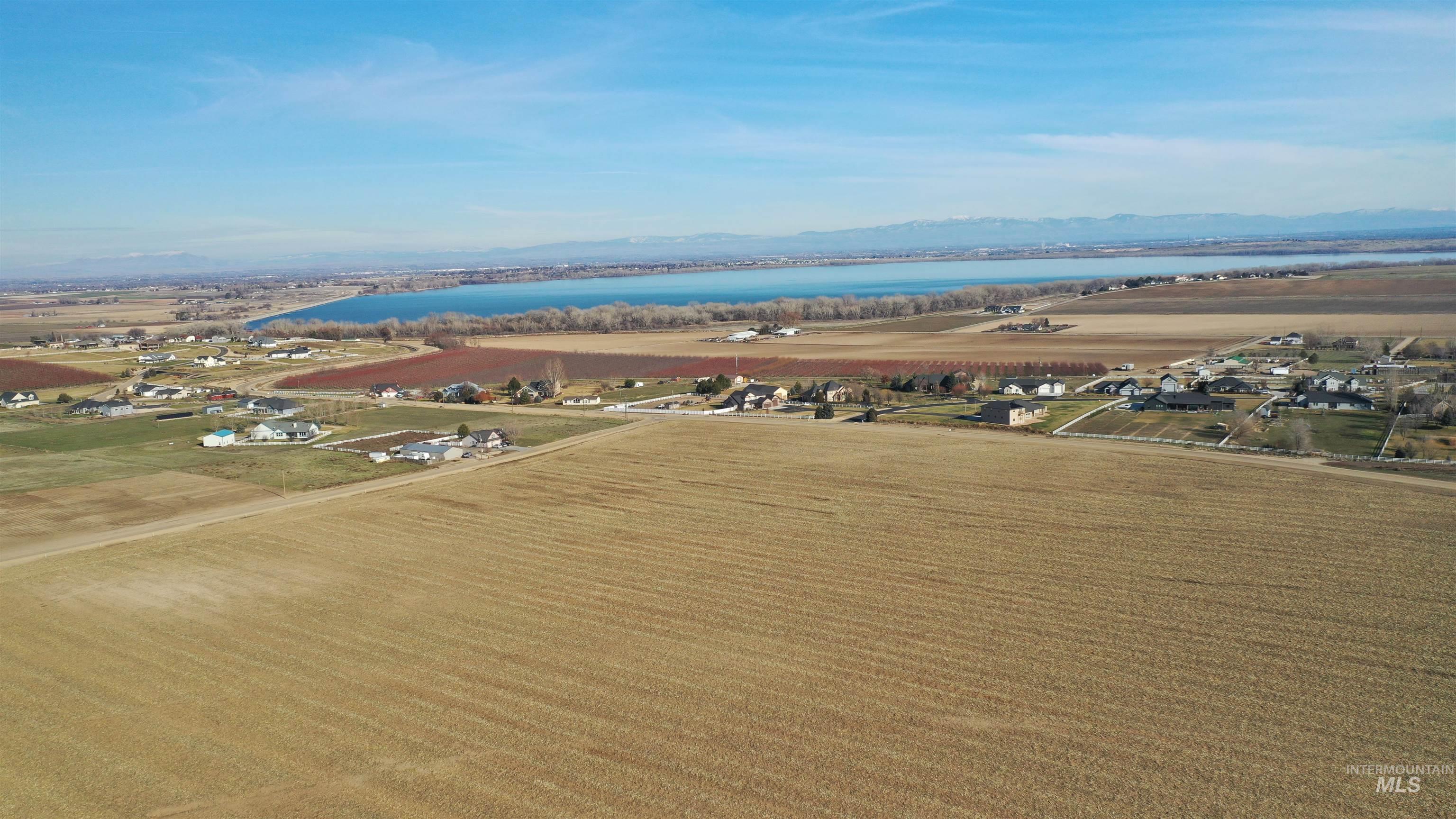 Aerial view of property's location with a water and mountain view, rows of crops, and rural landscape