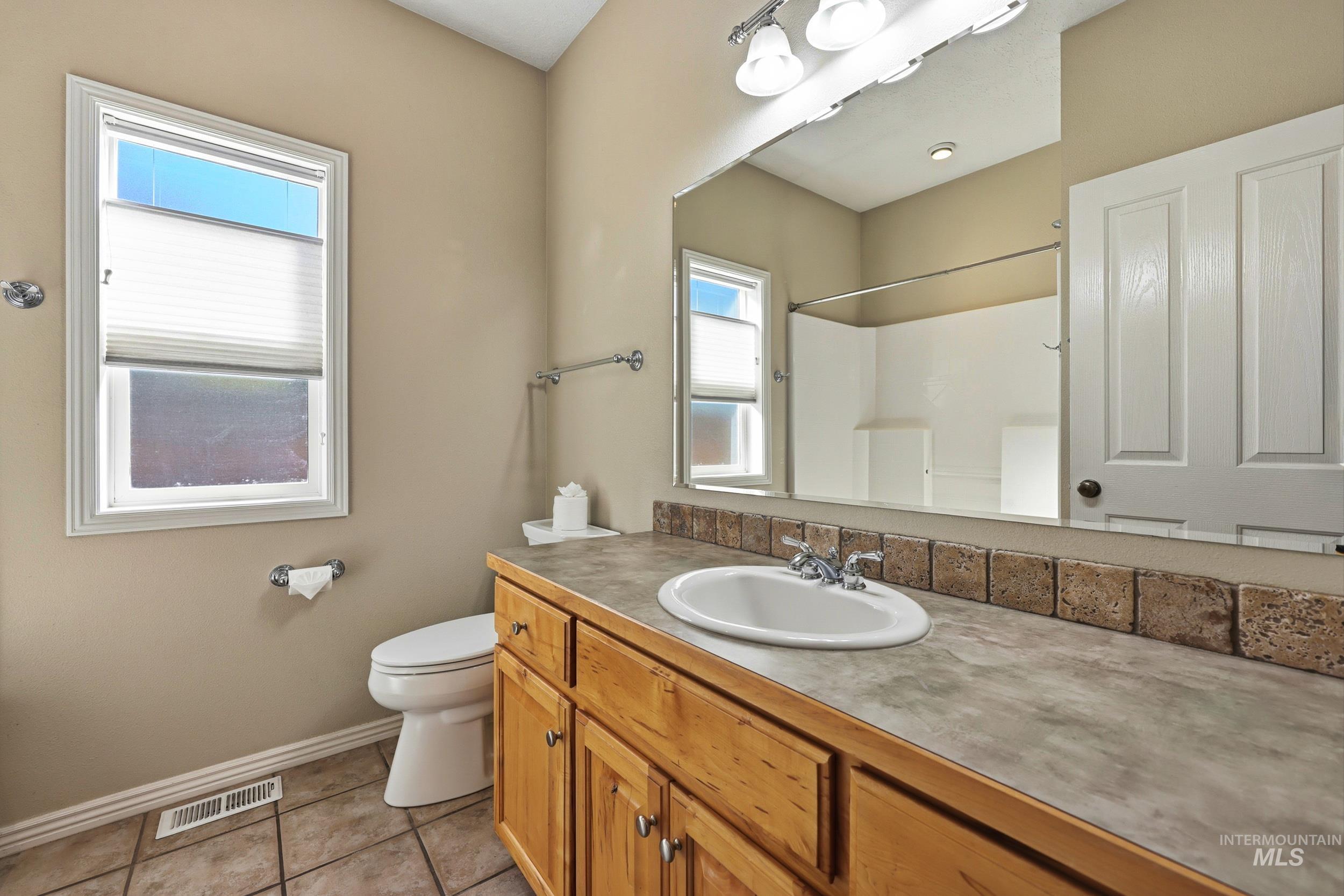 Bathroom with vanity, light tile patterned floors, and a shower