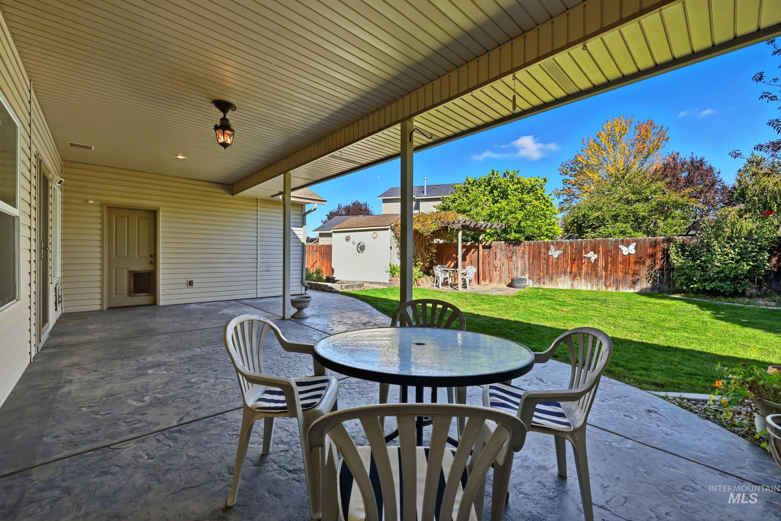 Fenced backyard with outdoor dining area, a patio, and an outbuilding