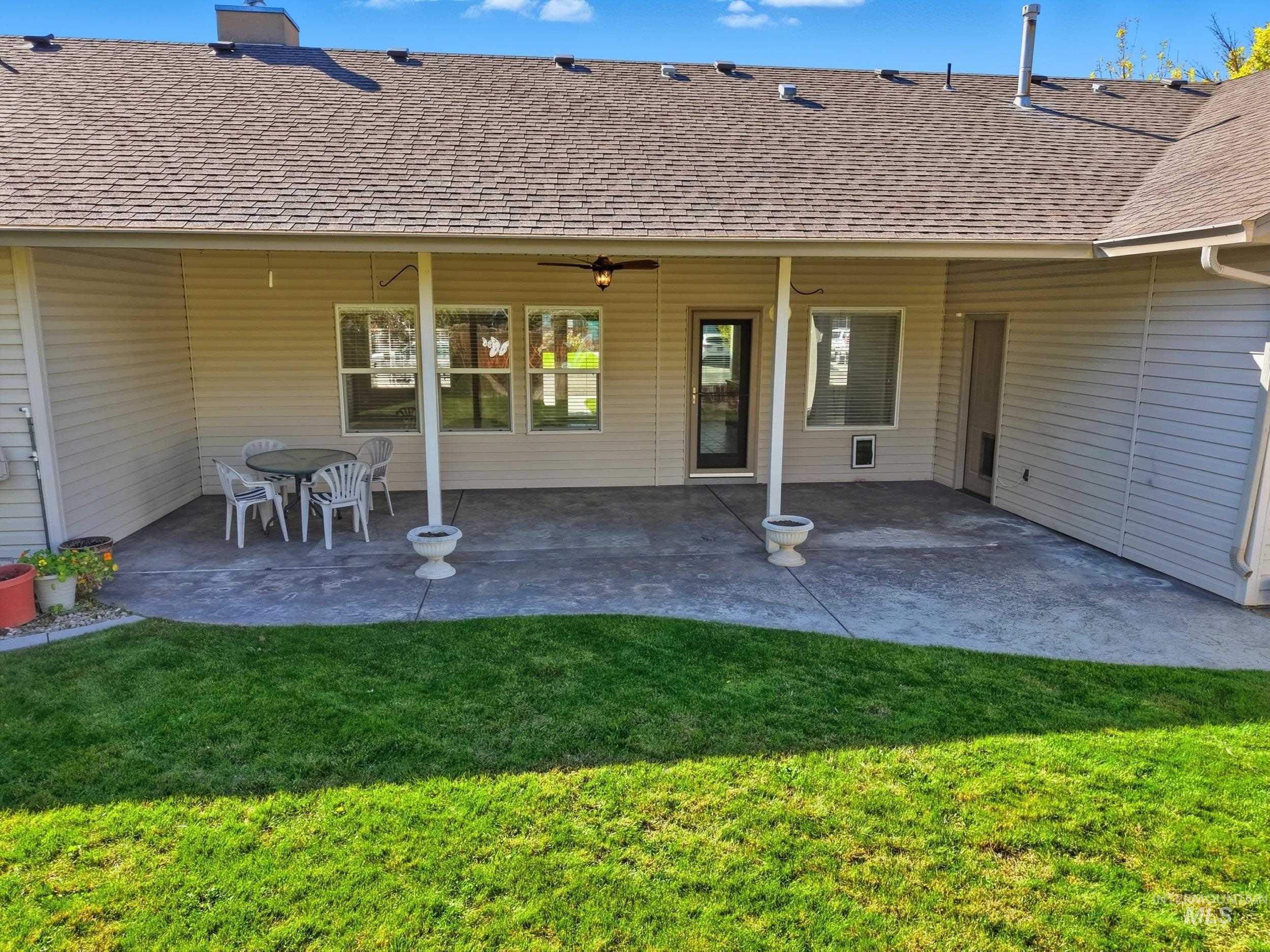 Rear view of property with a patio, a shingled roof, and a yard
