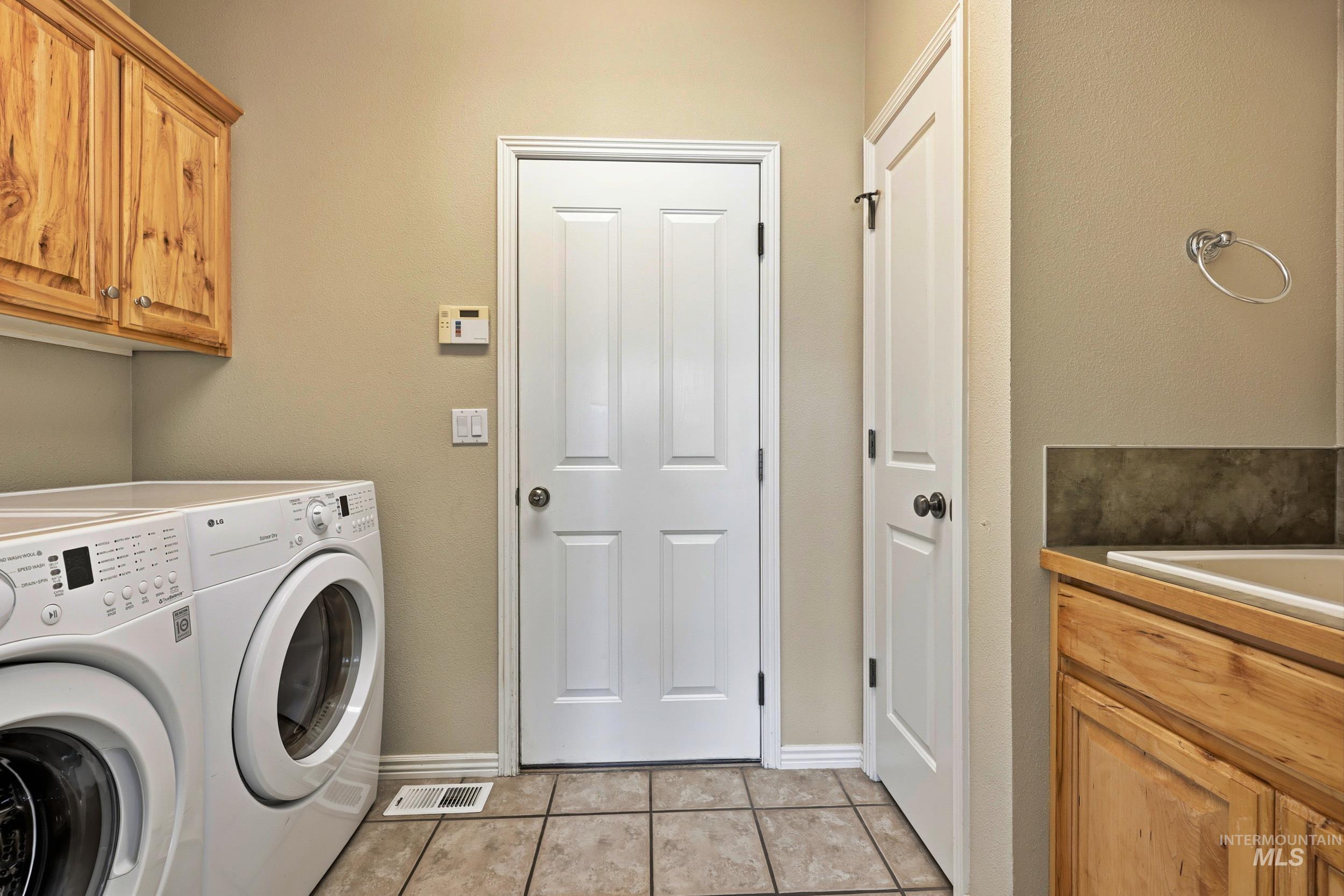 Laundry area with cabinet space, light tile patterned floors, and washer and dryer