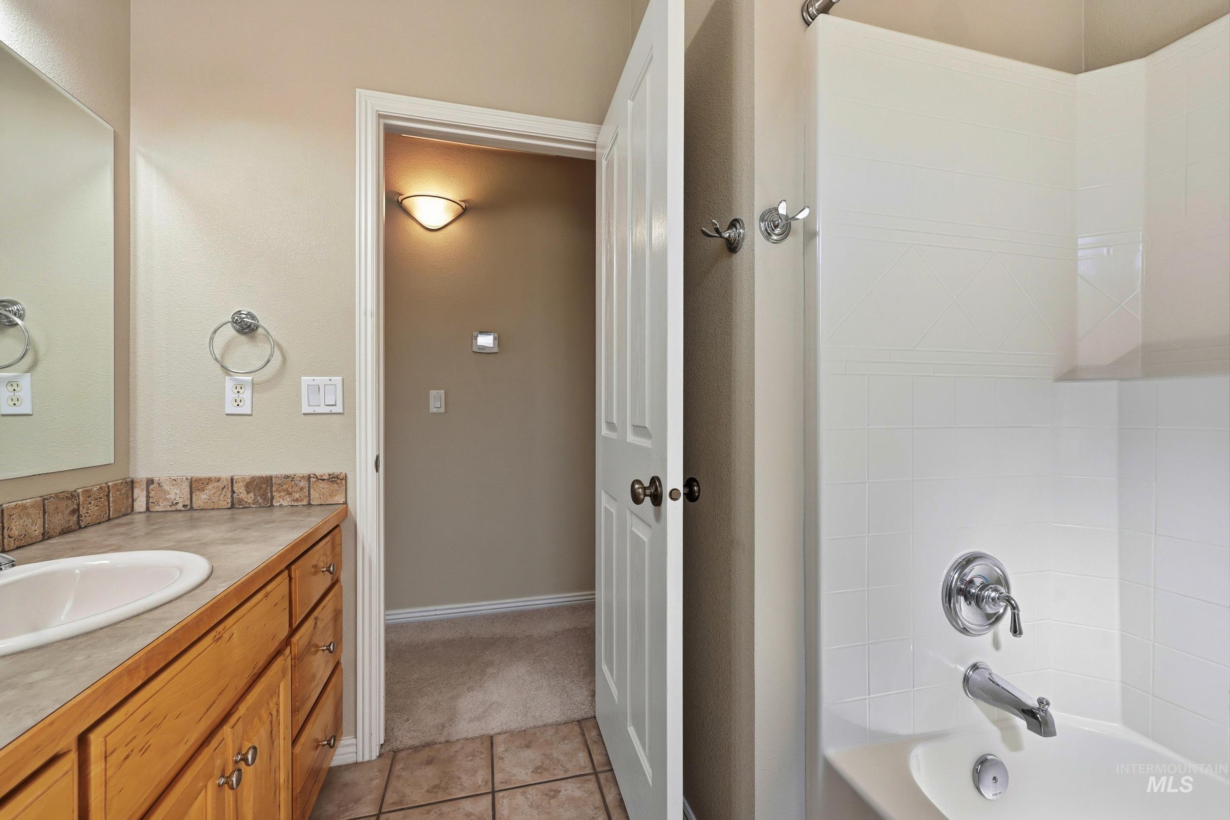 Bathroom featuring shower / washtub combination, vanity, light tile patterned floors, and light colored carpet