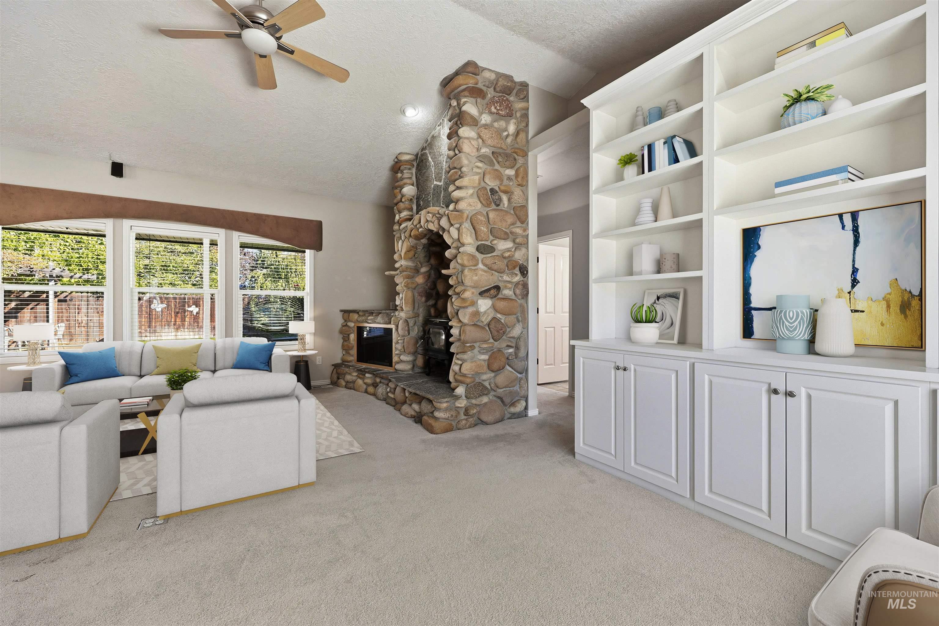 Living room with a textured ceiling, light colored carpet, vaulted ceiling, a ceiling fan, and a stone fireplace