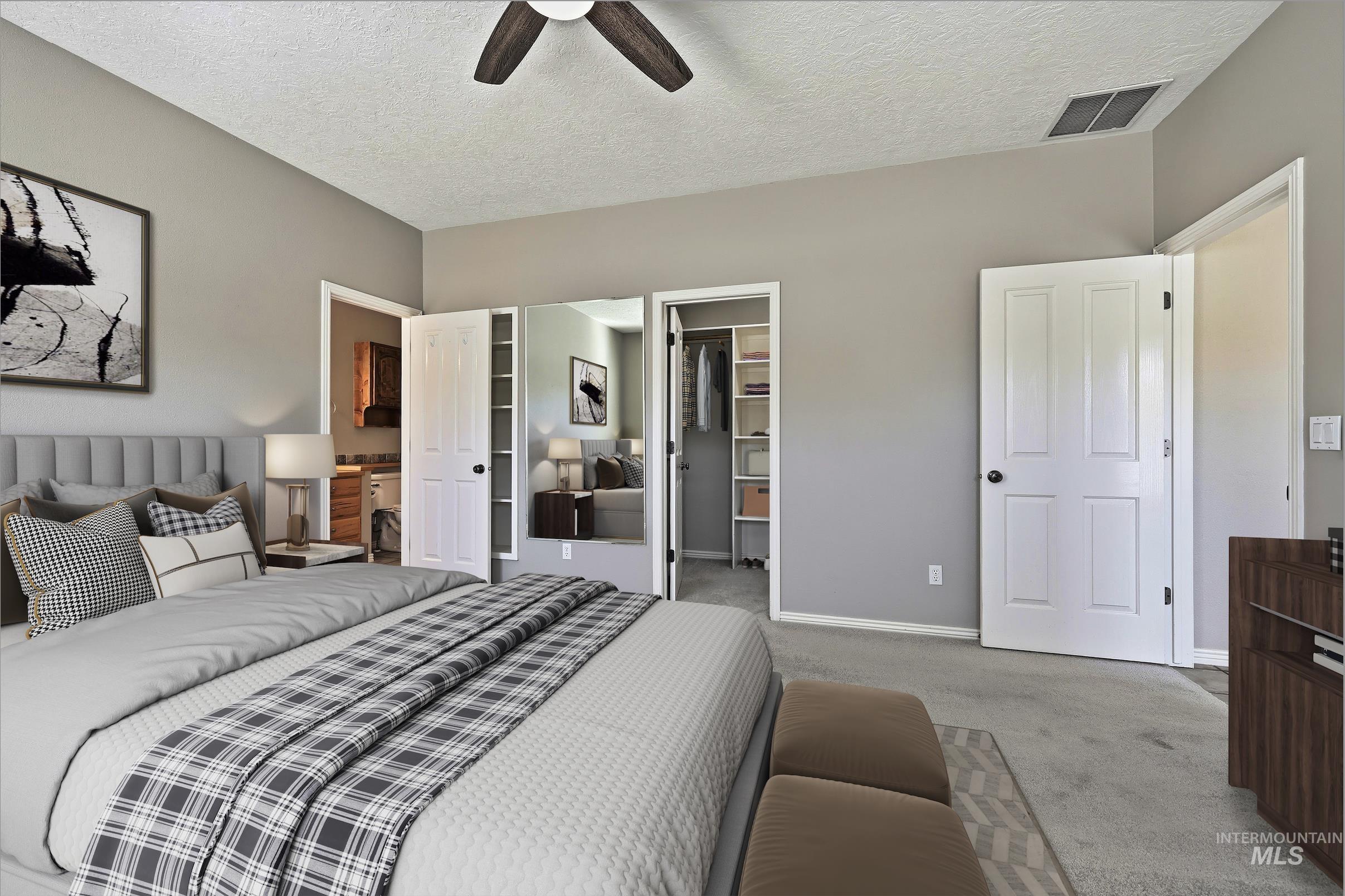 Carpeted bedroom featuring a spacious closet, a textured ceiling, and ceiling fan