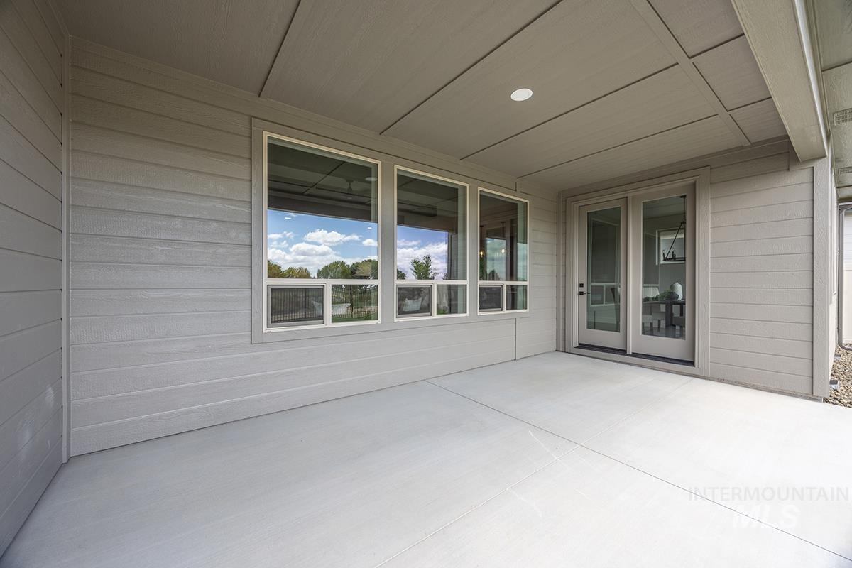 Covered patio featuring a concrete surface, horizontal siding, transom windows, and glass panel double doors