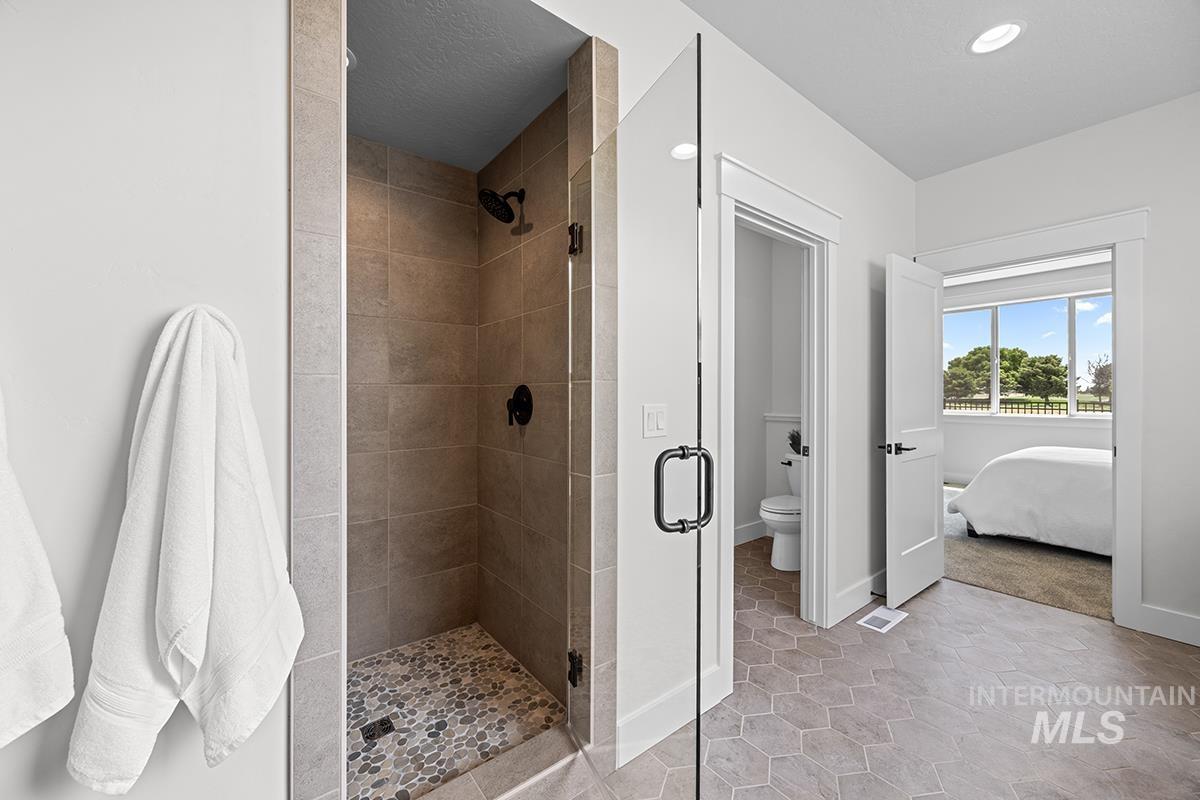 Walk-in shower featuring a pebble tile floor and matte black fixtures