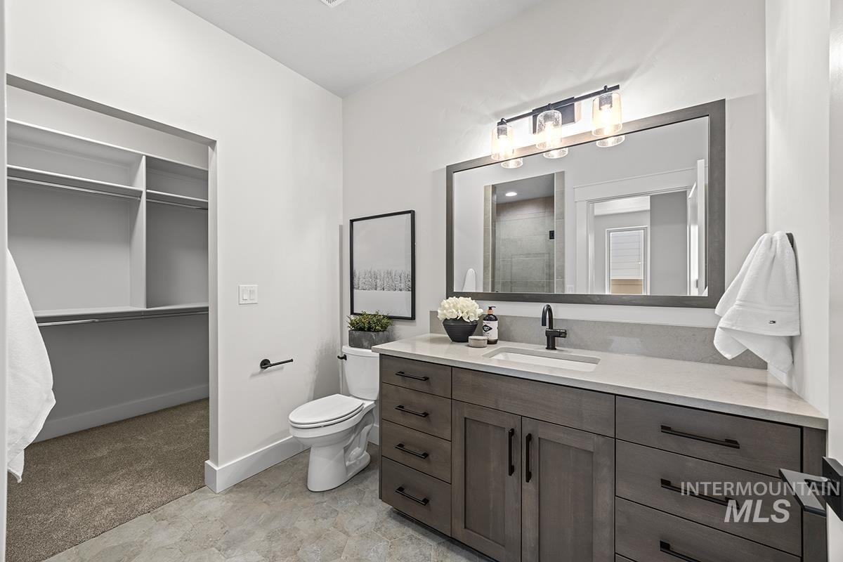 Well-appointed bathroom featuring a single vanity with a light-toned countertop, a rectangular sink with a matte black faucet, and a large framed mirror with overhead lighting