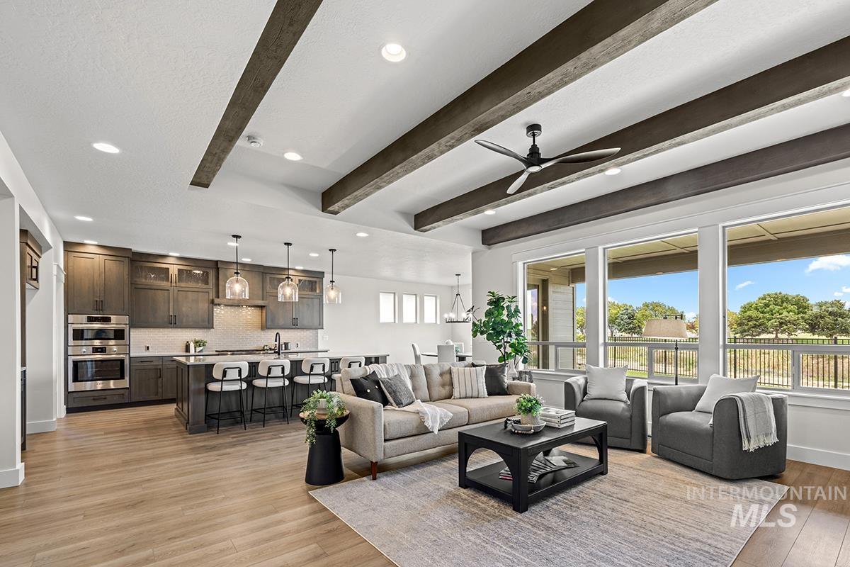 Open-concept living space featuring wood-finish flooring, exposed ceiling beams, recessed lighting, and large windows