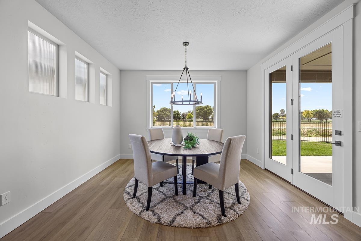 Dining area featuring wood-finish flooring, white baseboards, and a contemporary chandelier