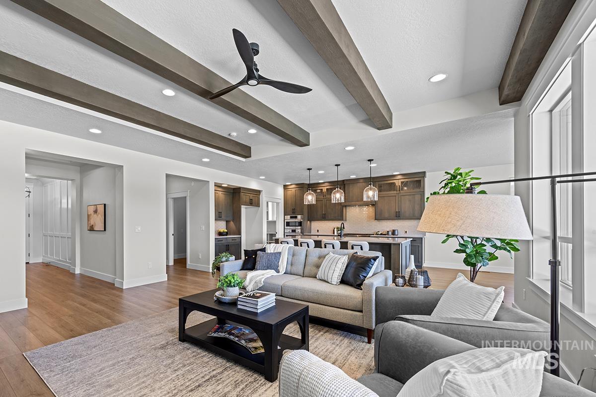 Open-concept living area featuring wood-finish flooring, exposed ceiling beams, recessed lighting, and a contemporary ceiling fan