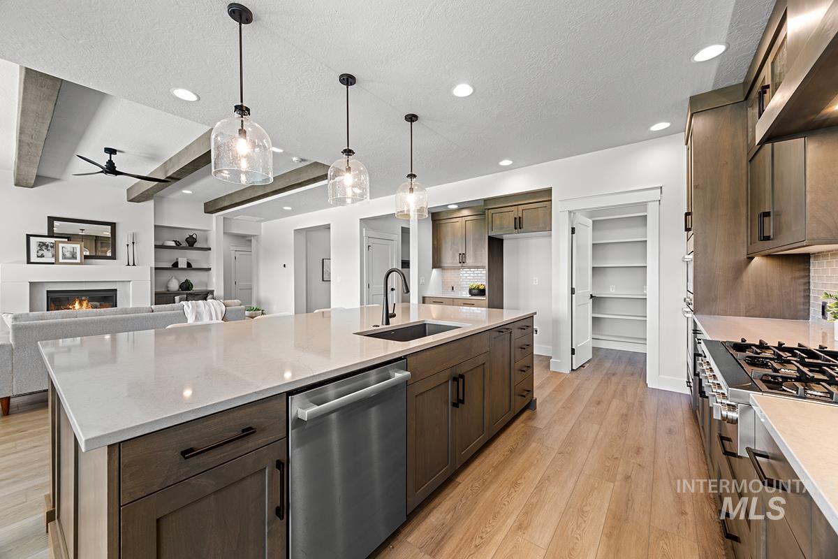Contemporary kitchen featuring a large island with an undermount sink, light-toned countertops, and wood-finish flooring