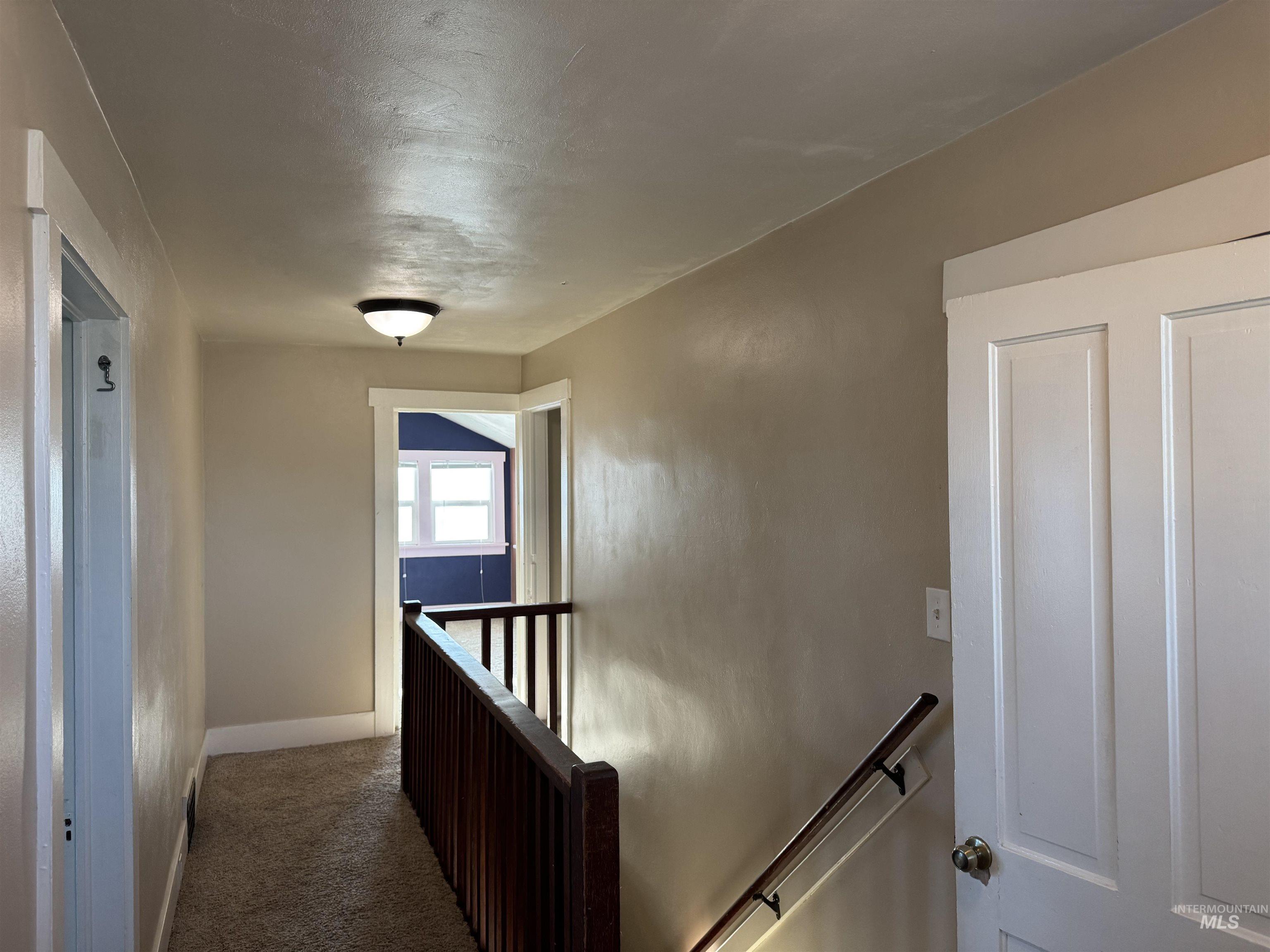 Corridor with an upstairs landing and carpet