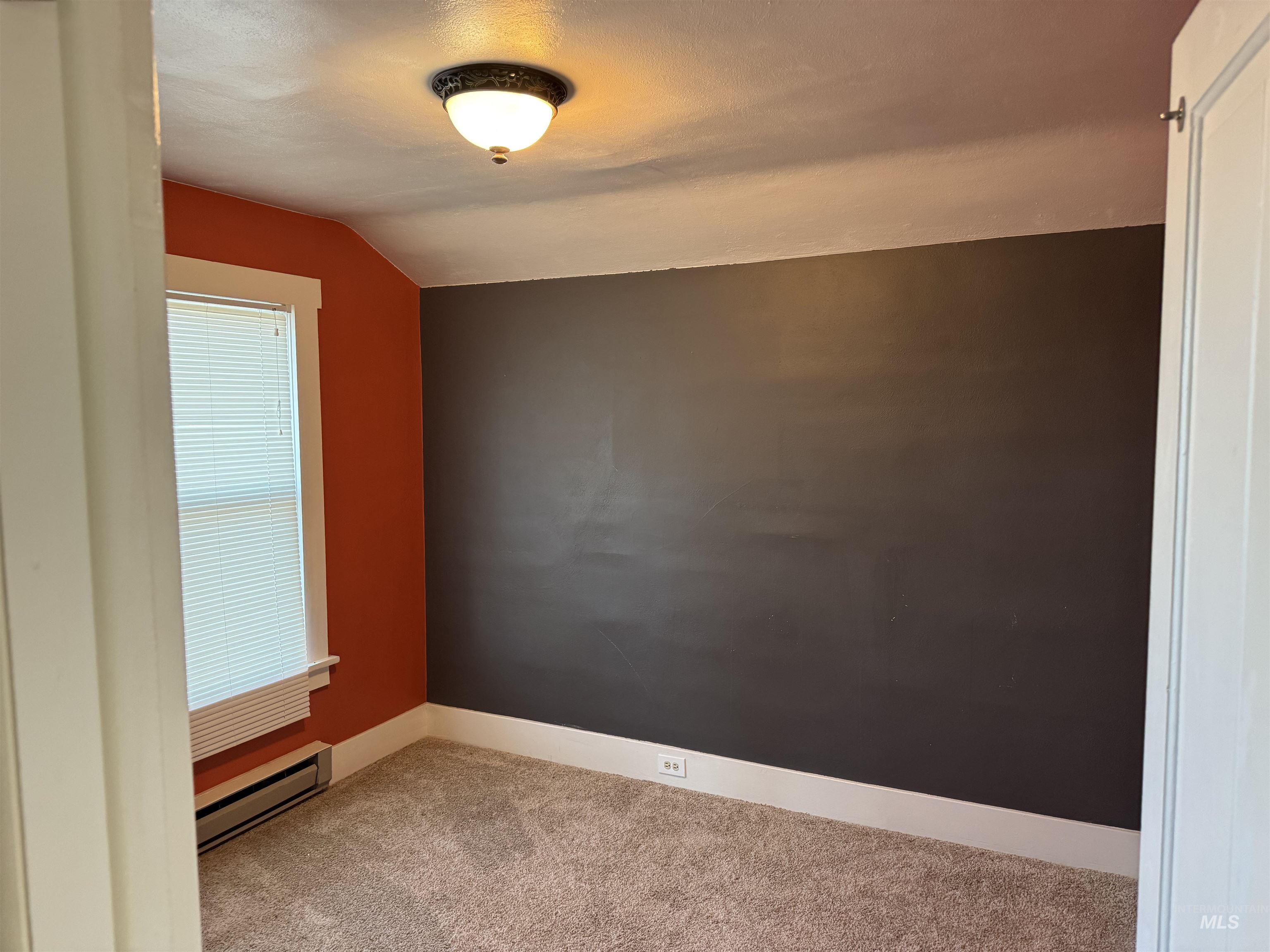 Additional living space featuring vaulted ceiling, a baseboard radiator, and carpet floors