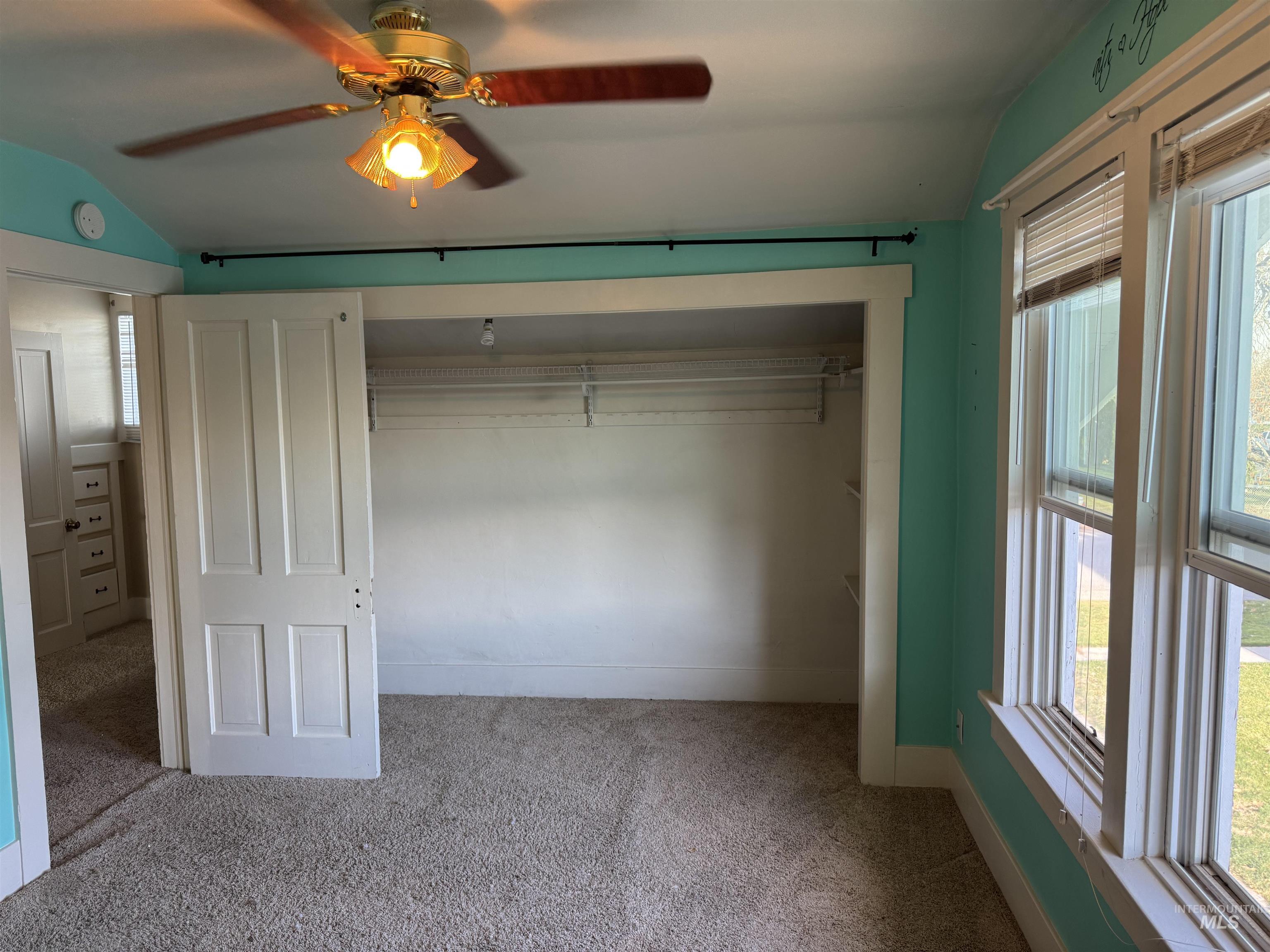 Unfurnished bedroom with a closet, vaulted ceiling, carpet flooring, and ceiling fan