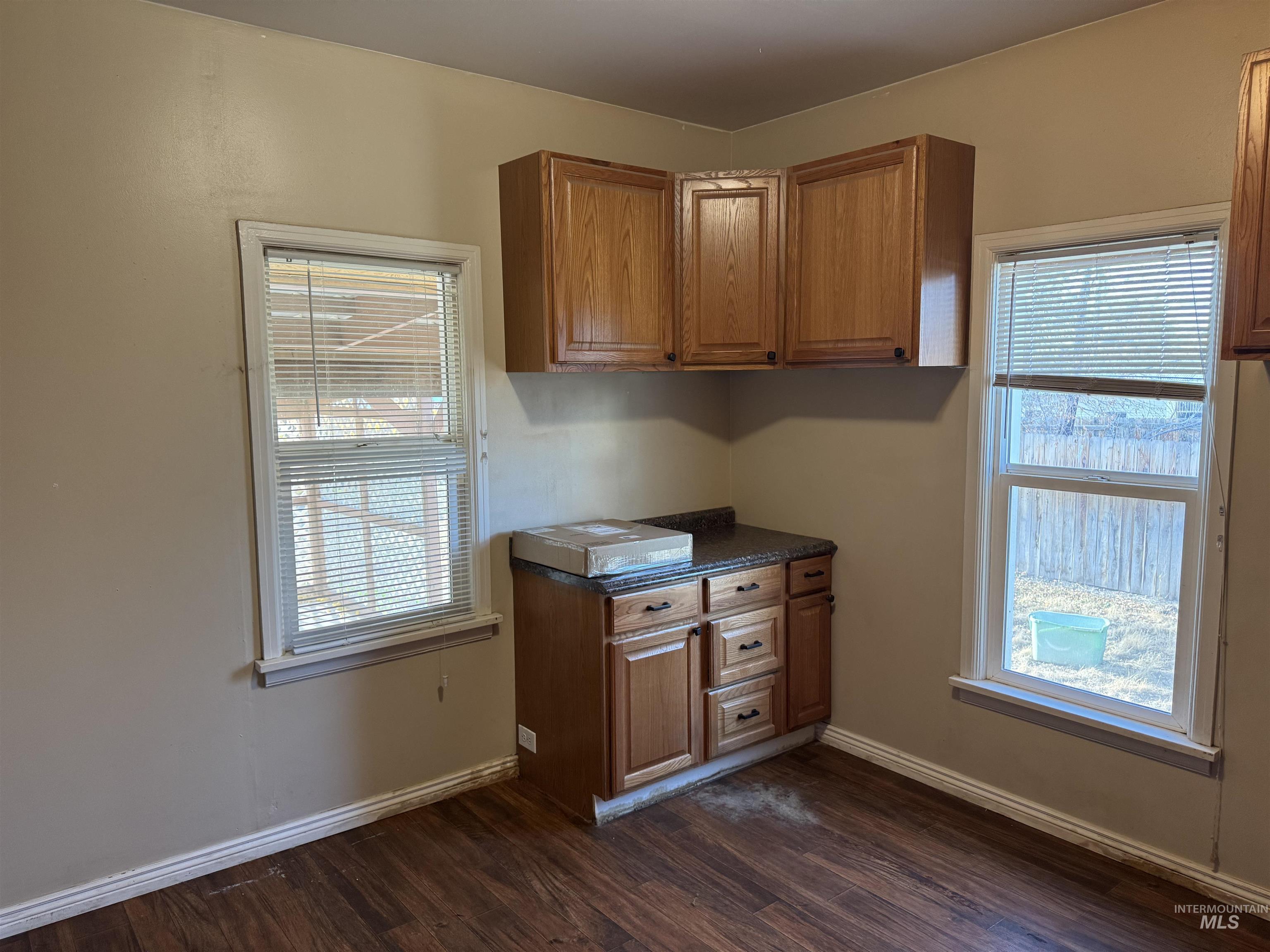 Kitchen with dark countertops, dark wood-style flooring, and brown cabinets