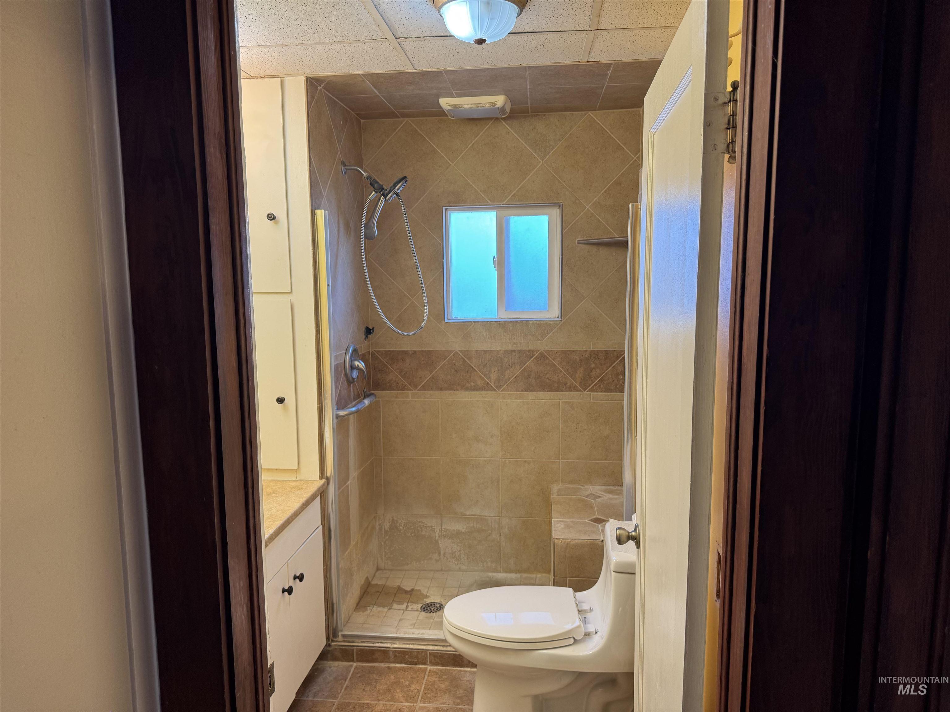 Bathroom with a stall shower, dark tile patterned floors, and vanity