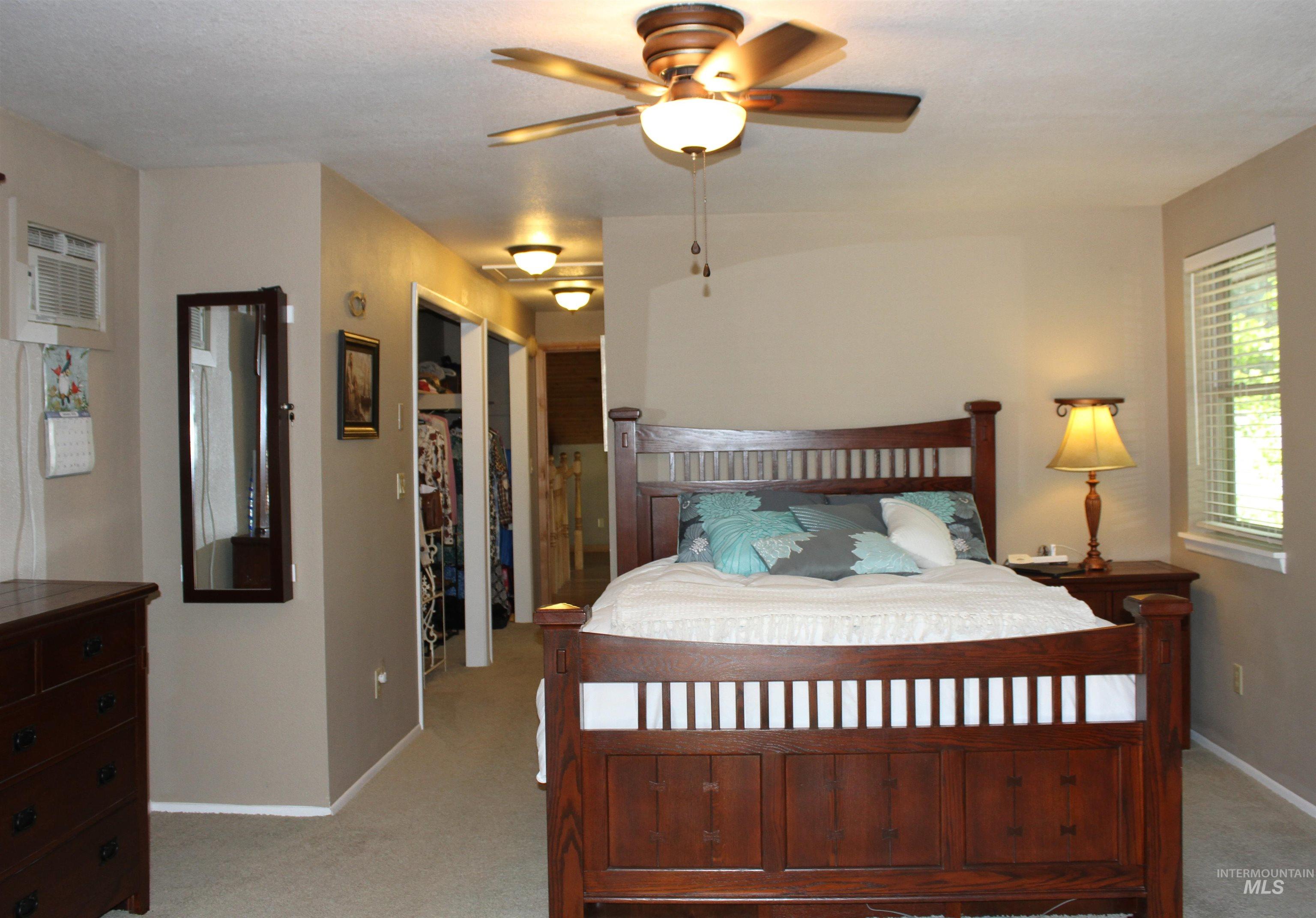 Bedroom with light carpet, a walk in closet, and ceiling fan