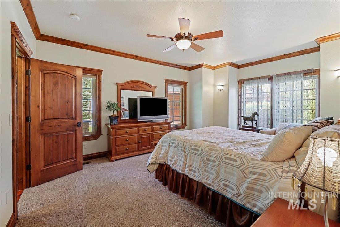 Bedroom featuring light colored carpet, crown molding, and a ceiling fan