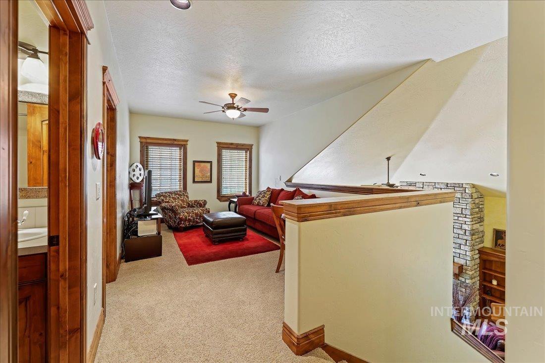 Living room featuring ceiling fan, light carpet, and a textured ceiling