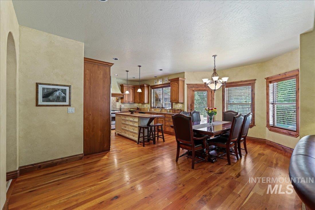 Dining space featuring wood flooring, a chandelier, a textured ceiling, and arched walkways