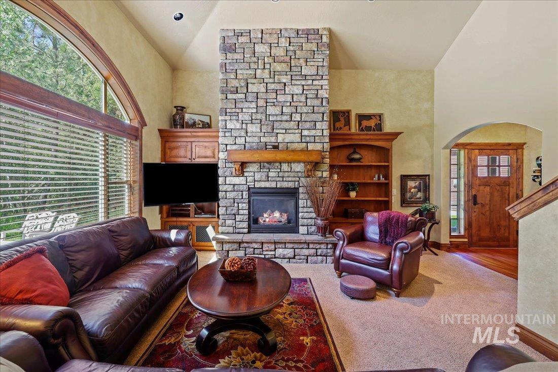 Living room with a stone fireplace a high ceiling, and arched walkways
