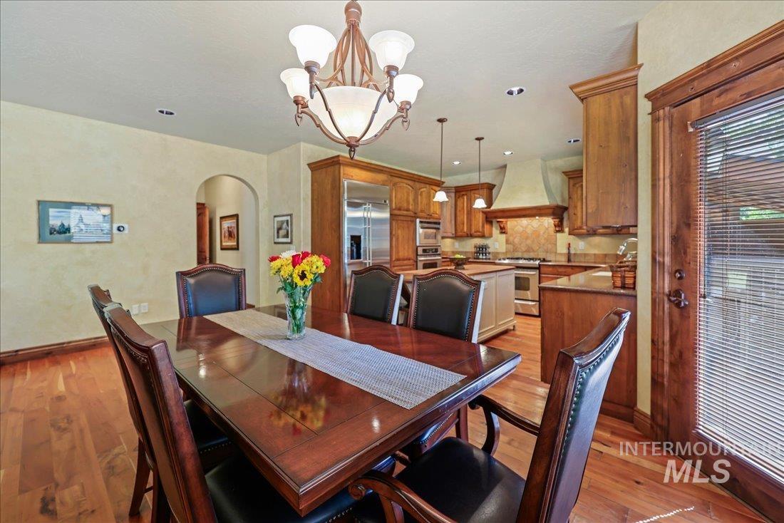 Dining space featuring arched walkways, wood floors, a chandelier, and recessed lighting