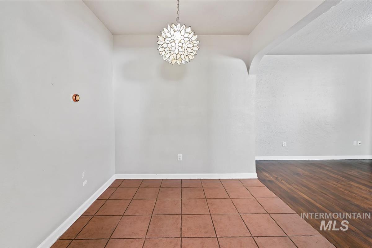 Spare room with dark tile patterned flooring and a chandelier