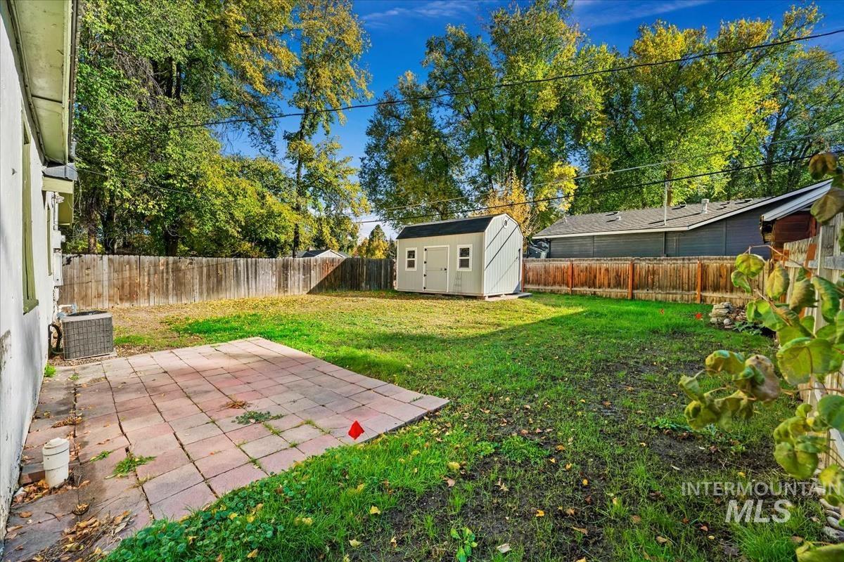 Fenced backyard featuring a patio and a shed