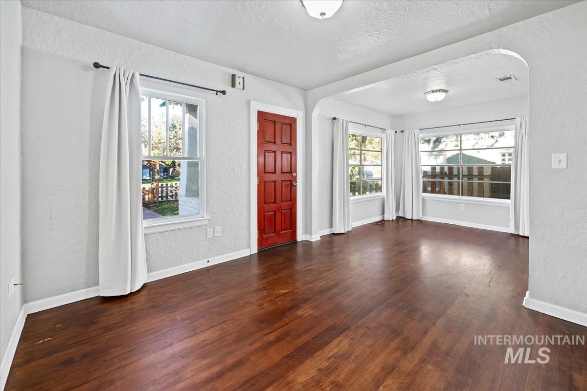 Entryway with a textured wall, arched walkways, plenty of natural light, a textured ceiling, and dark wood finished floors