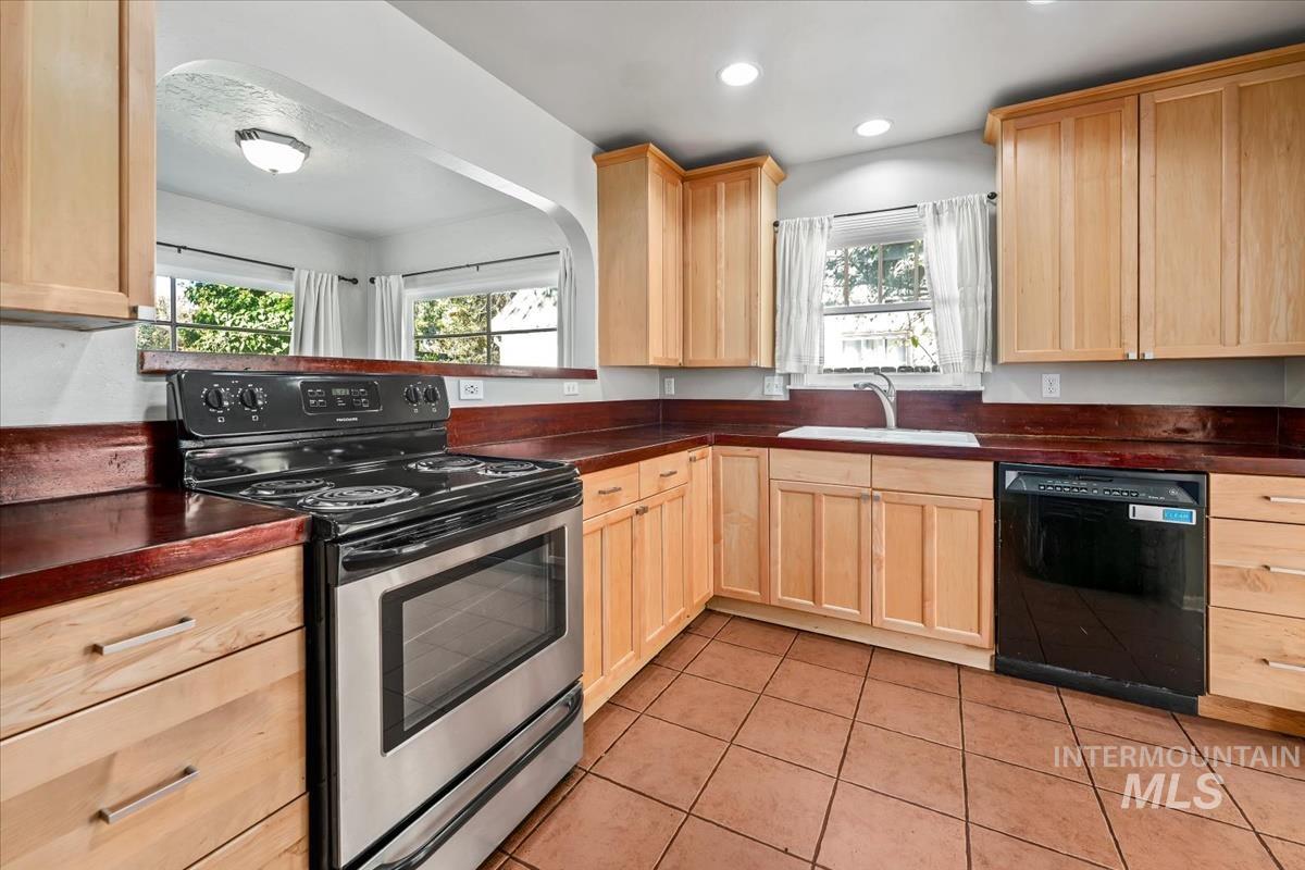 Kitchen featuring stainless steel electric range oven, light brown cabinets, dark countertops, and recessed lighting
