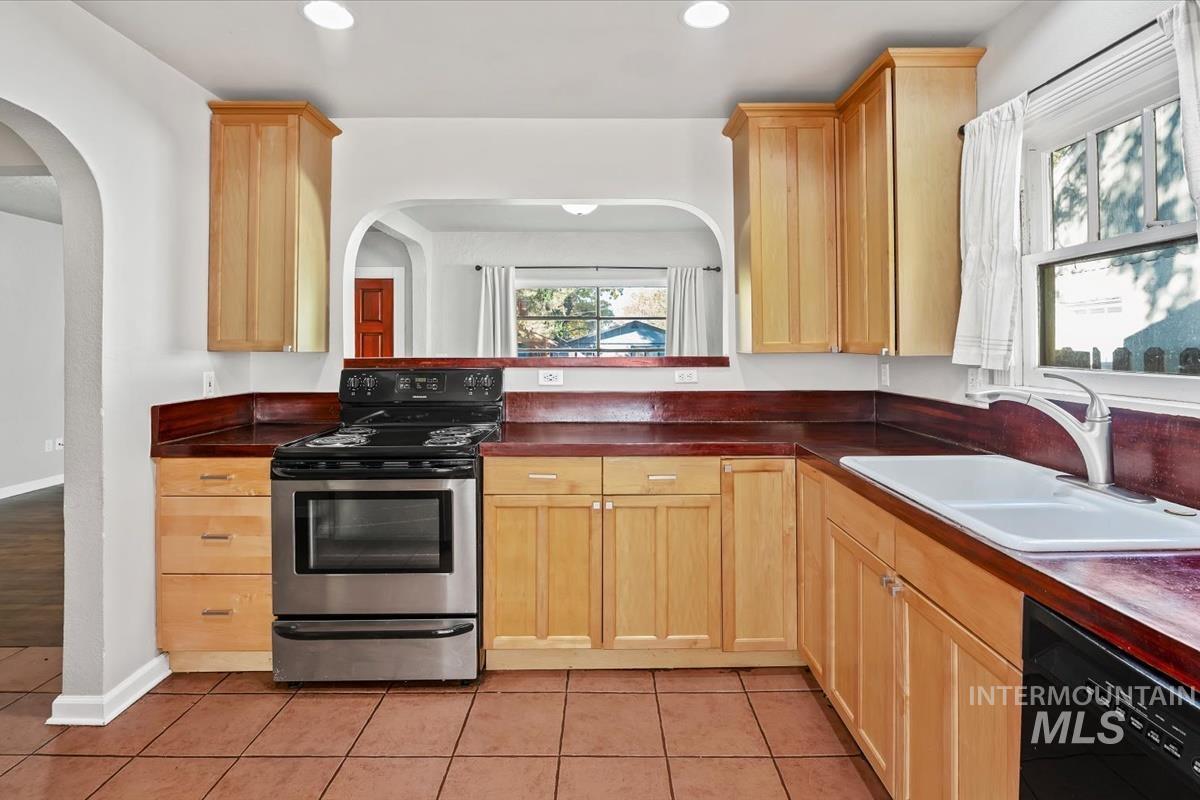 Kitchen with stainless steel range with electric stovetop, light brown cabinets, dishwasher, dark countertops, and recessed lighting
