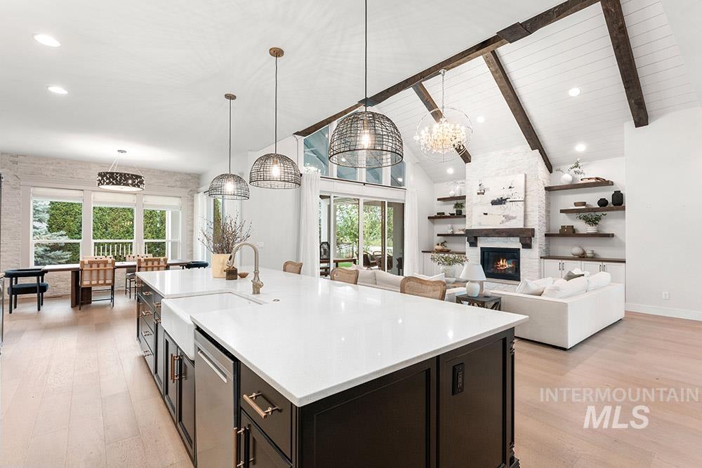 Kitchen with a large fireplace, beamed ceiling, dark cabinets, high vaulted ceiling, and decorative light fixtures