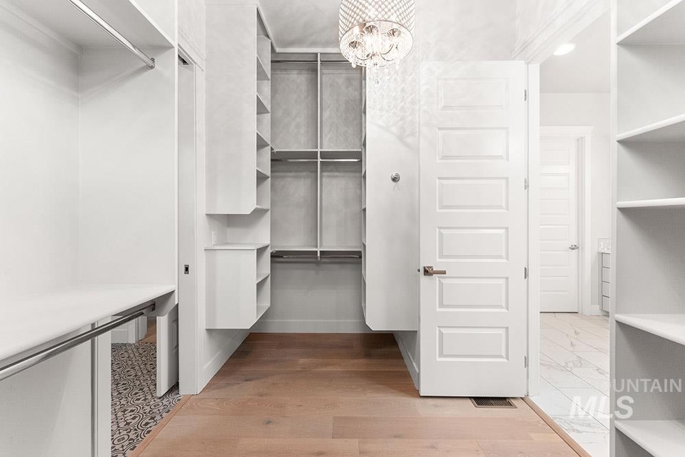 Walk in closet featuring a chandelier and light wood-style flooring