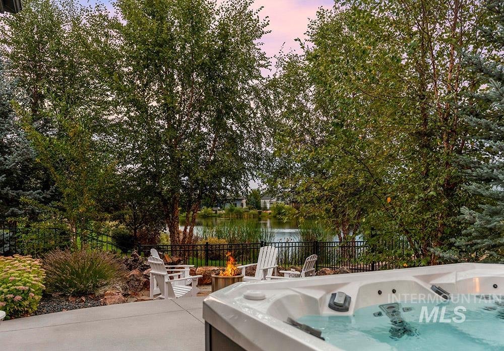 View of patio with a hot tub and a water view