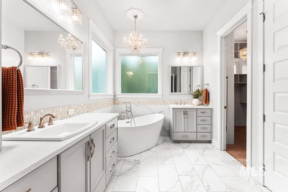 Full bathroom with two vanities, a soaking tub, tile walls, a wainscoted wall, and a walk in closet