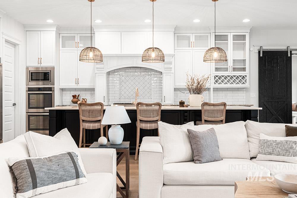 Kitchen with glass insert cabinets, white cabinetry, open floor plan, tasteful backsplash, and recessed lighting