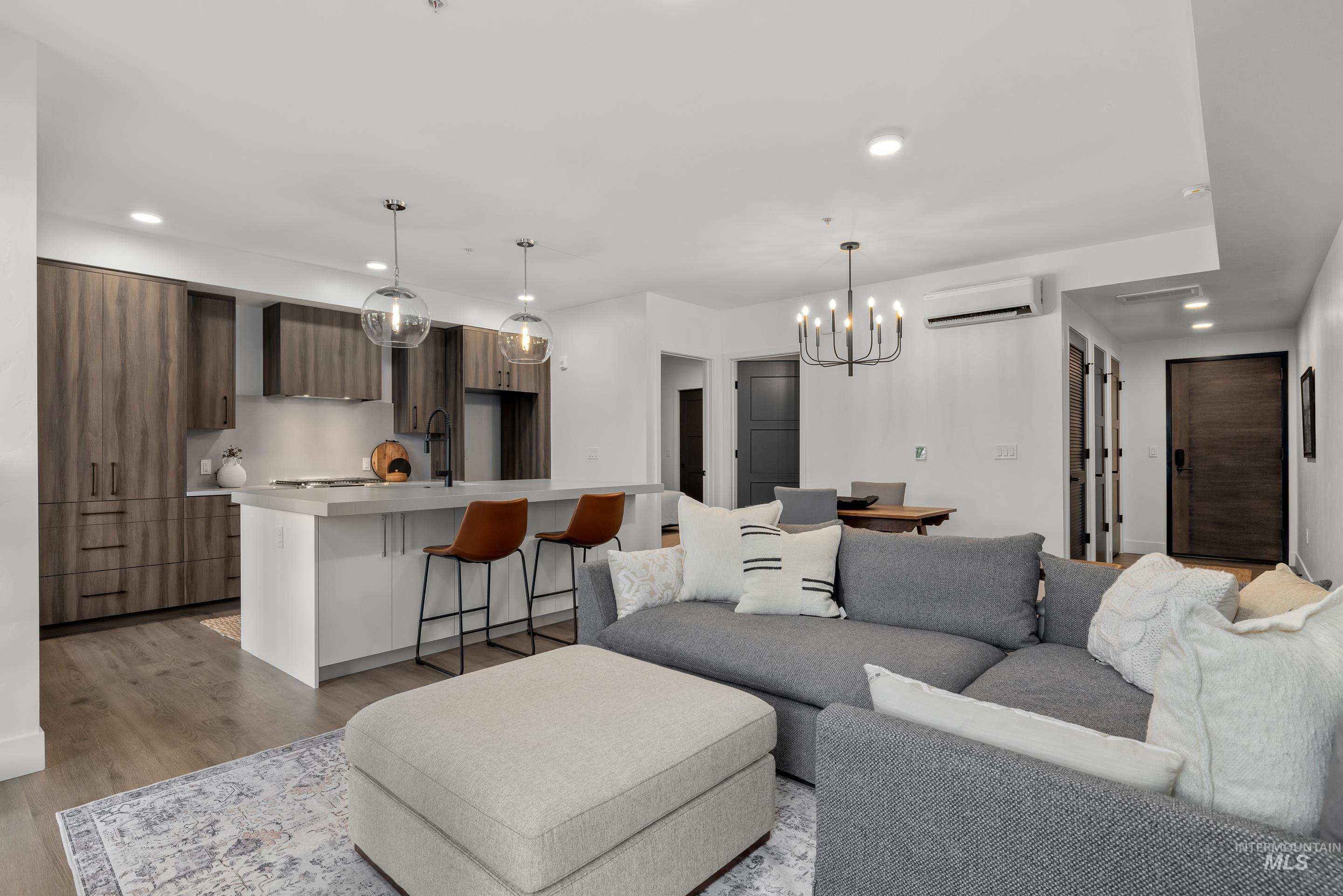 Living room featuring recessed lighting, light wood-type flooring, a chandelier, and a wall mounted AC