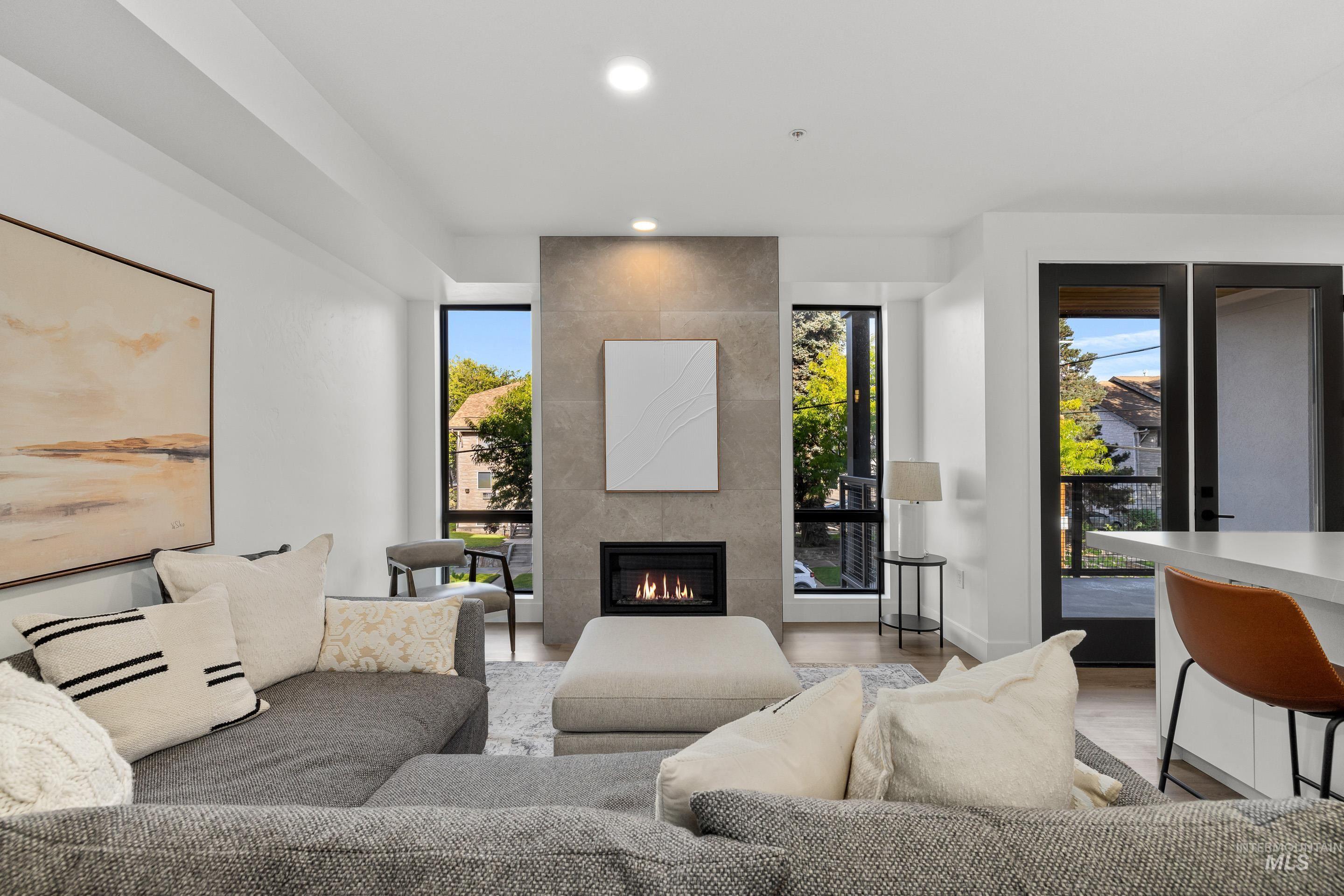 Living area with recessed lighting, plenty of natural light, a tiled fireplace, and light wood-type flooring