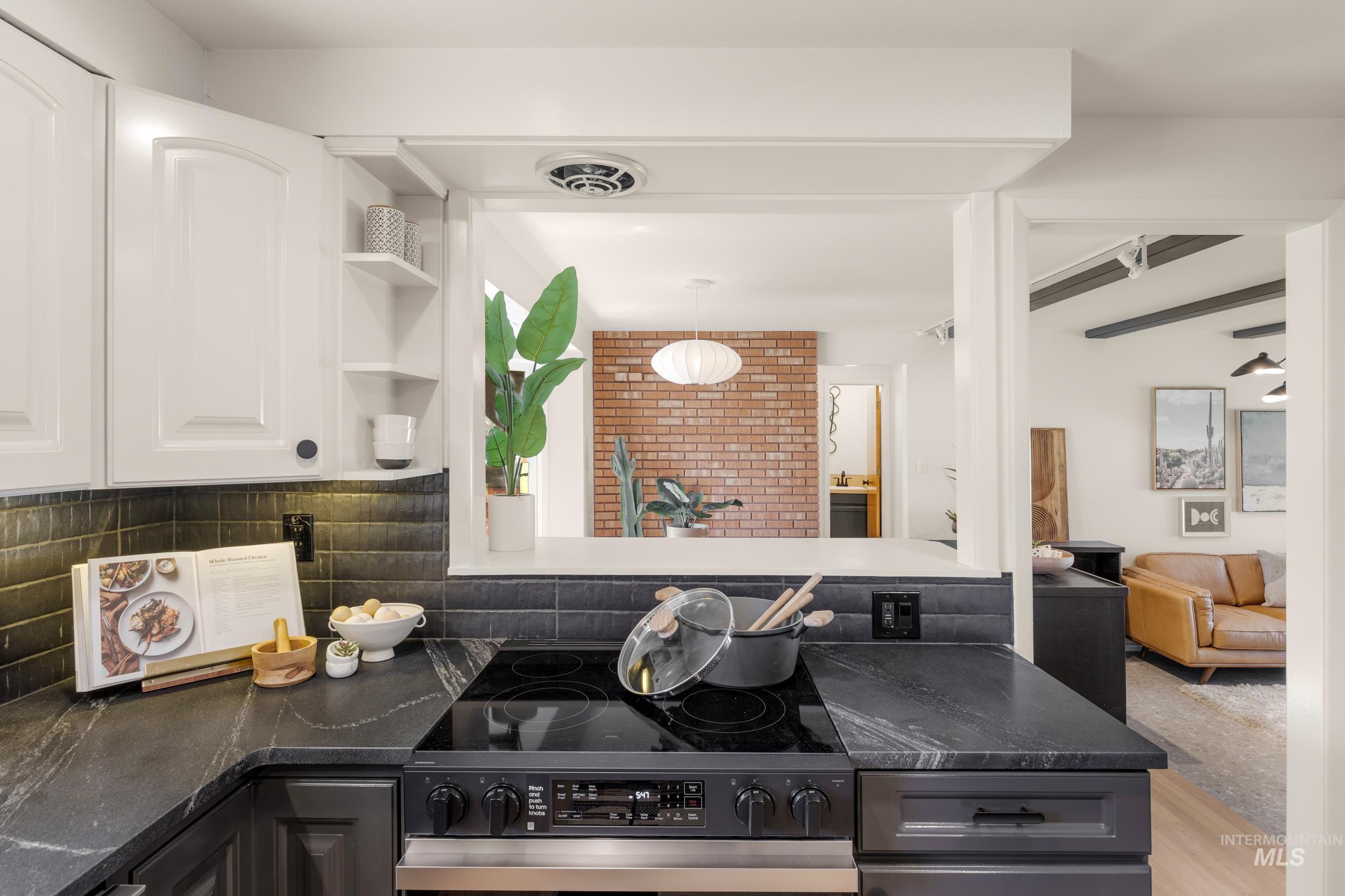 Kitchen featuring stainless steel electric range oven, open shelves, white cabinetry, and dark stone countertops