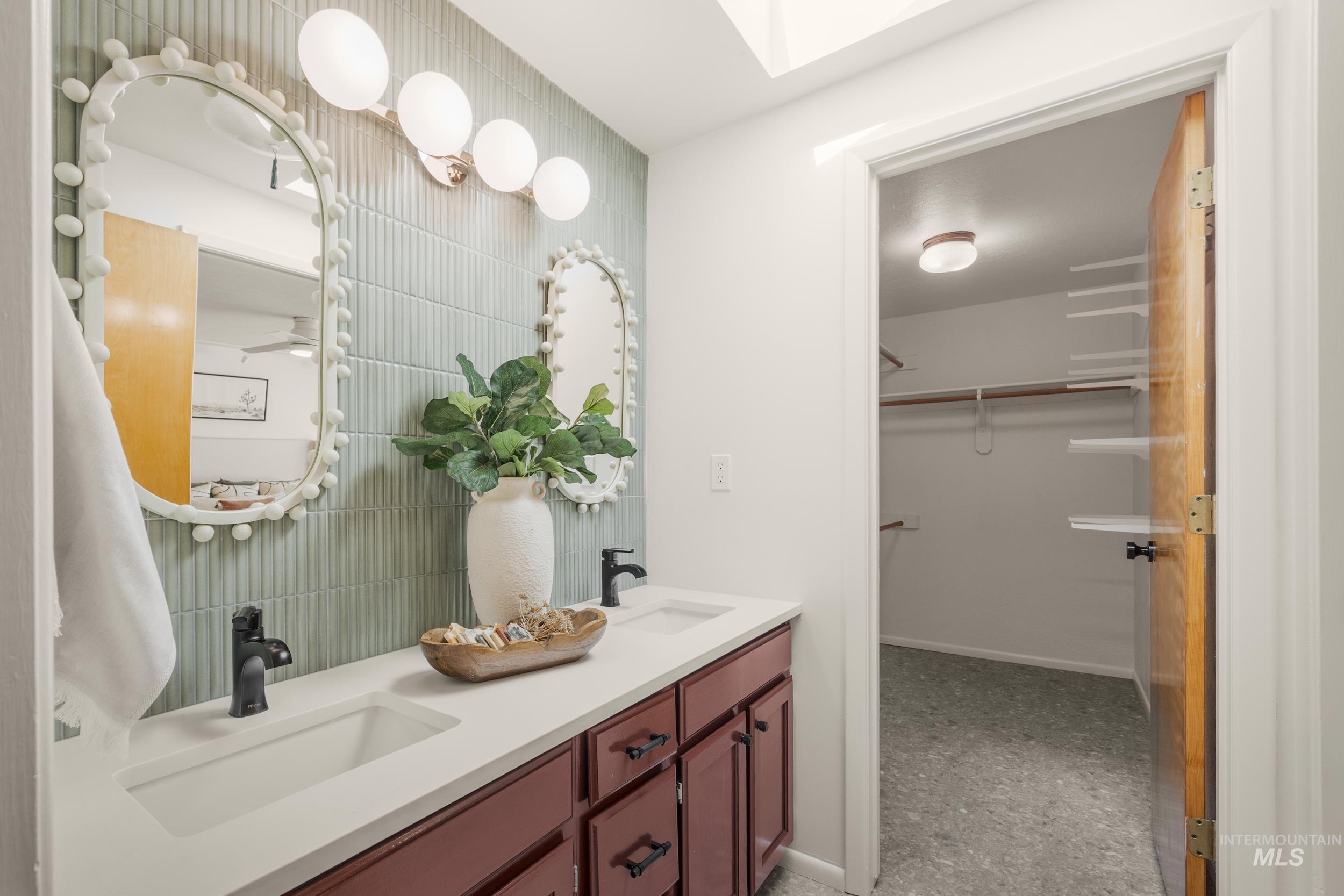 Full bath featuring a walk in closet, double vanity, and a skylight