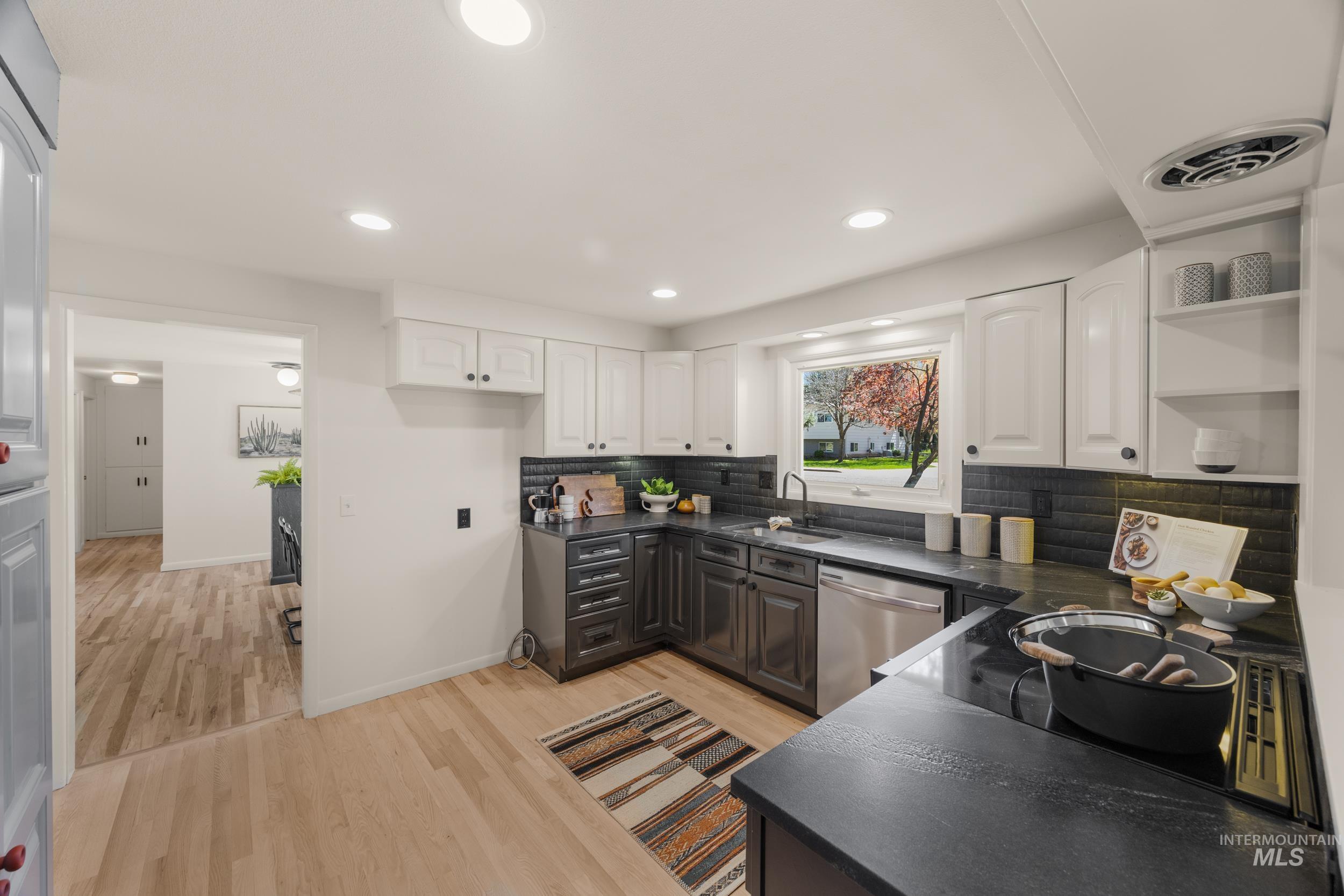 Kitchen with two tone cabinets, dishwasher, light wood finished floors, recessed lighting, and open shelves