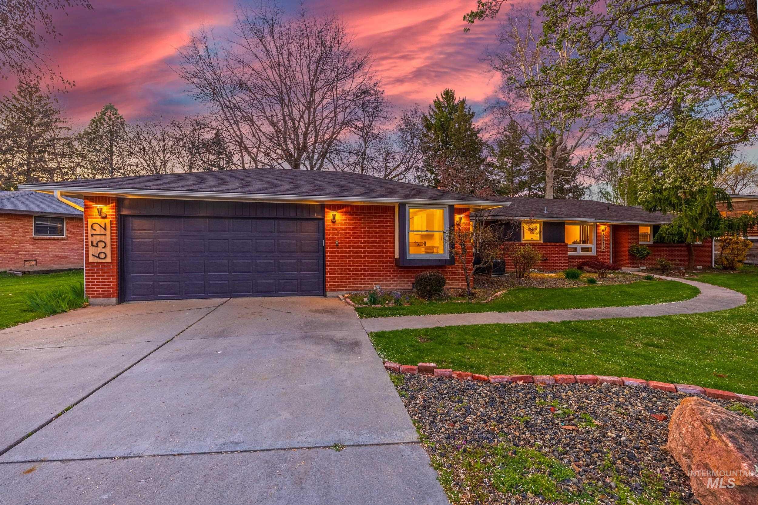 Ranch-style home with a lawn, concrete driveway, a garage, and brick siding