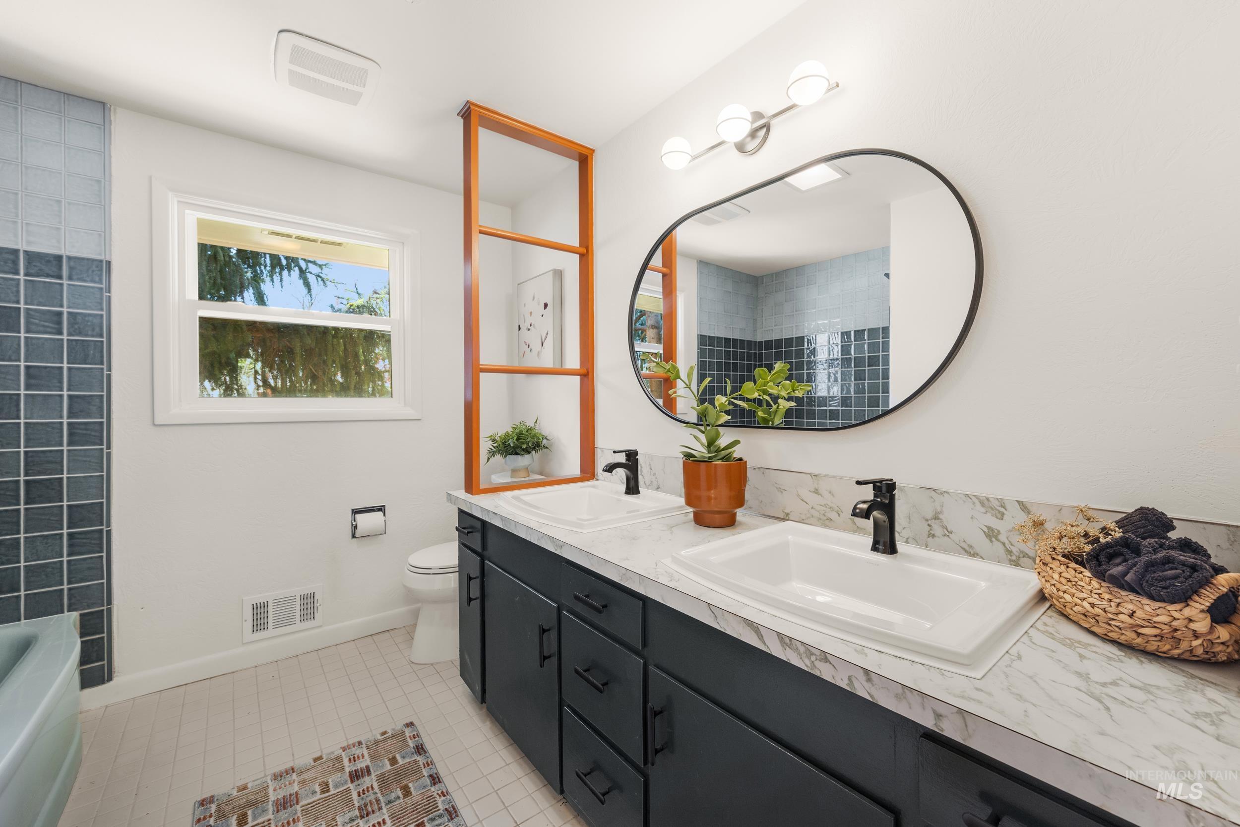 Full bath with light tile patterned flooring, double vanity, and a bath