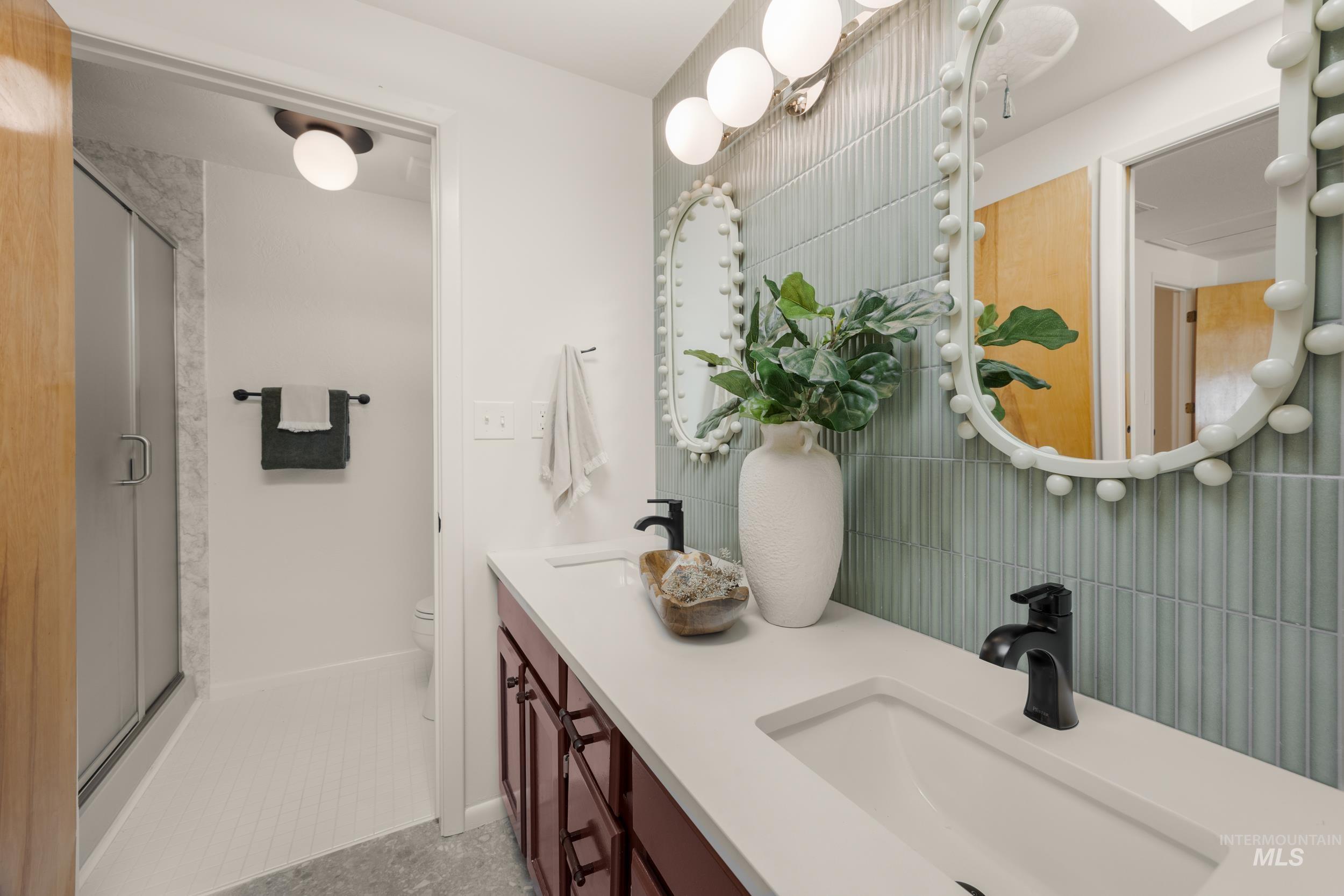 Full bathroom featuring double vanity, a stall shower, and light tile patterned floors