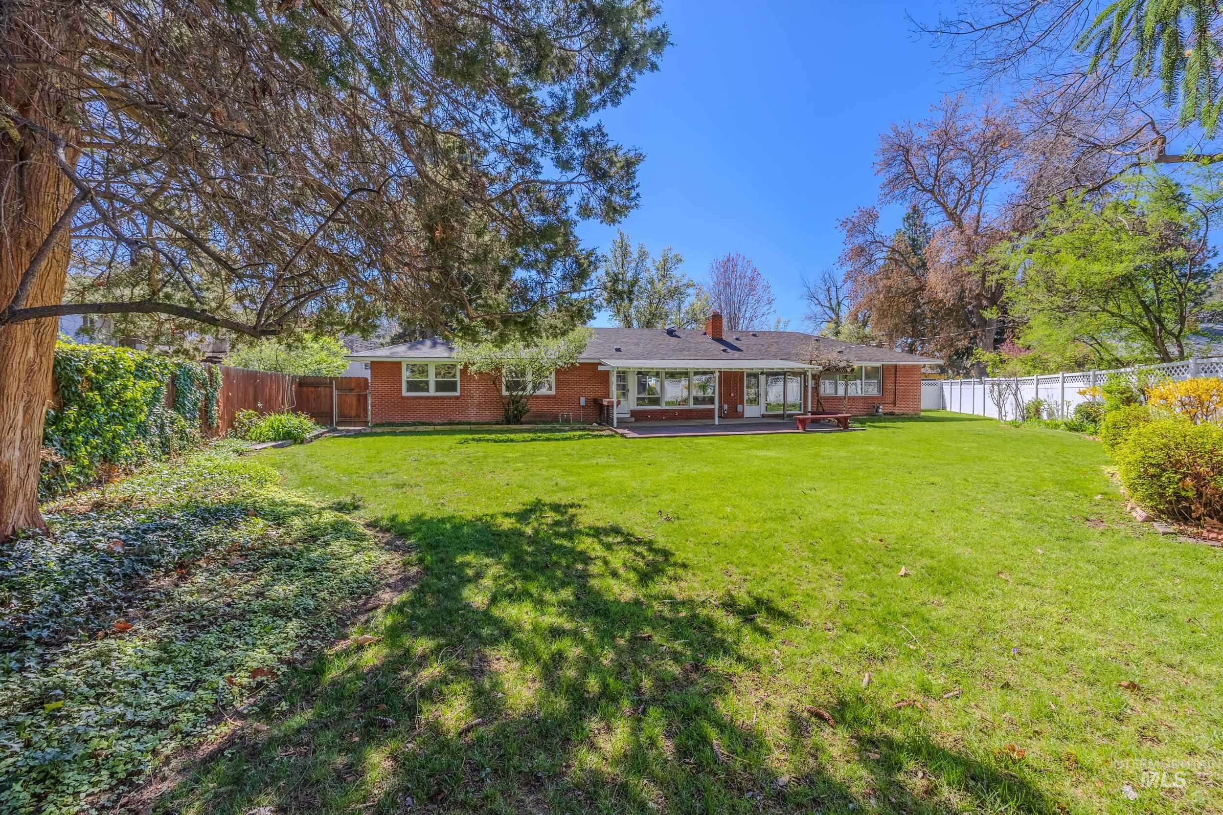 Rear view of property with brick siding, a fenced backyard, a chimney, and a patio area