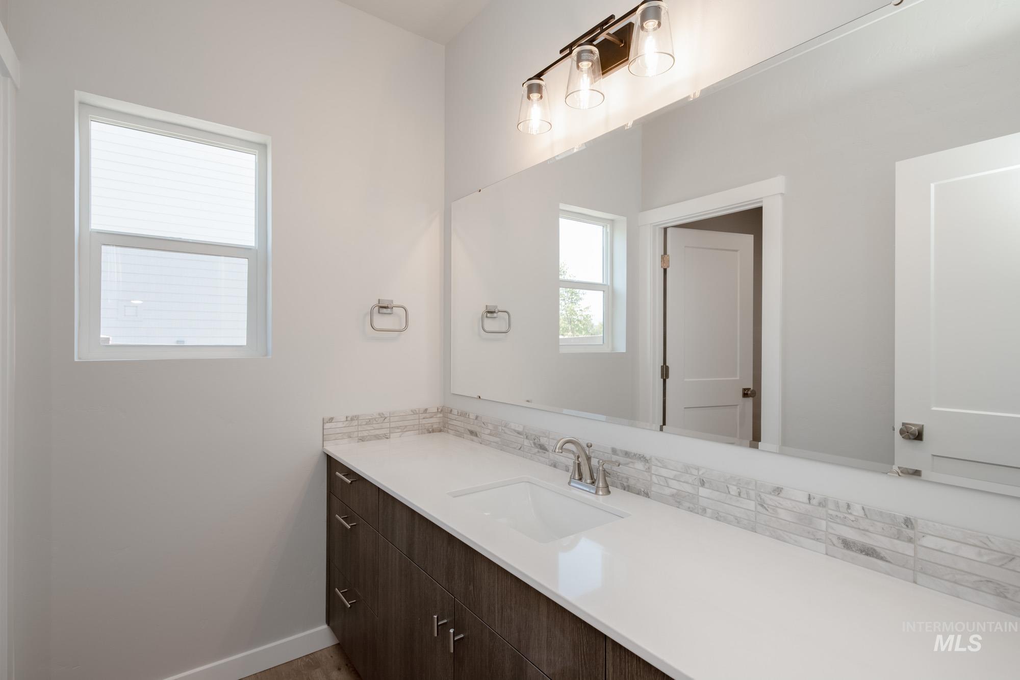 Bathroom with vanity and tasteful backsplash
