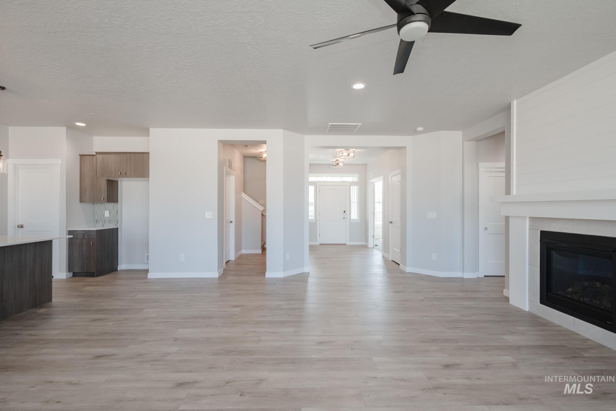 Unfurnished living room with light wood-type flooring, a tile fireplace, recessed lighting, a ceiling fan, and a textured ceiling