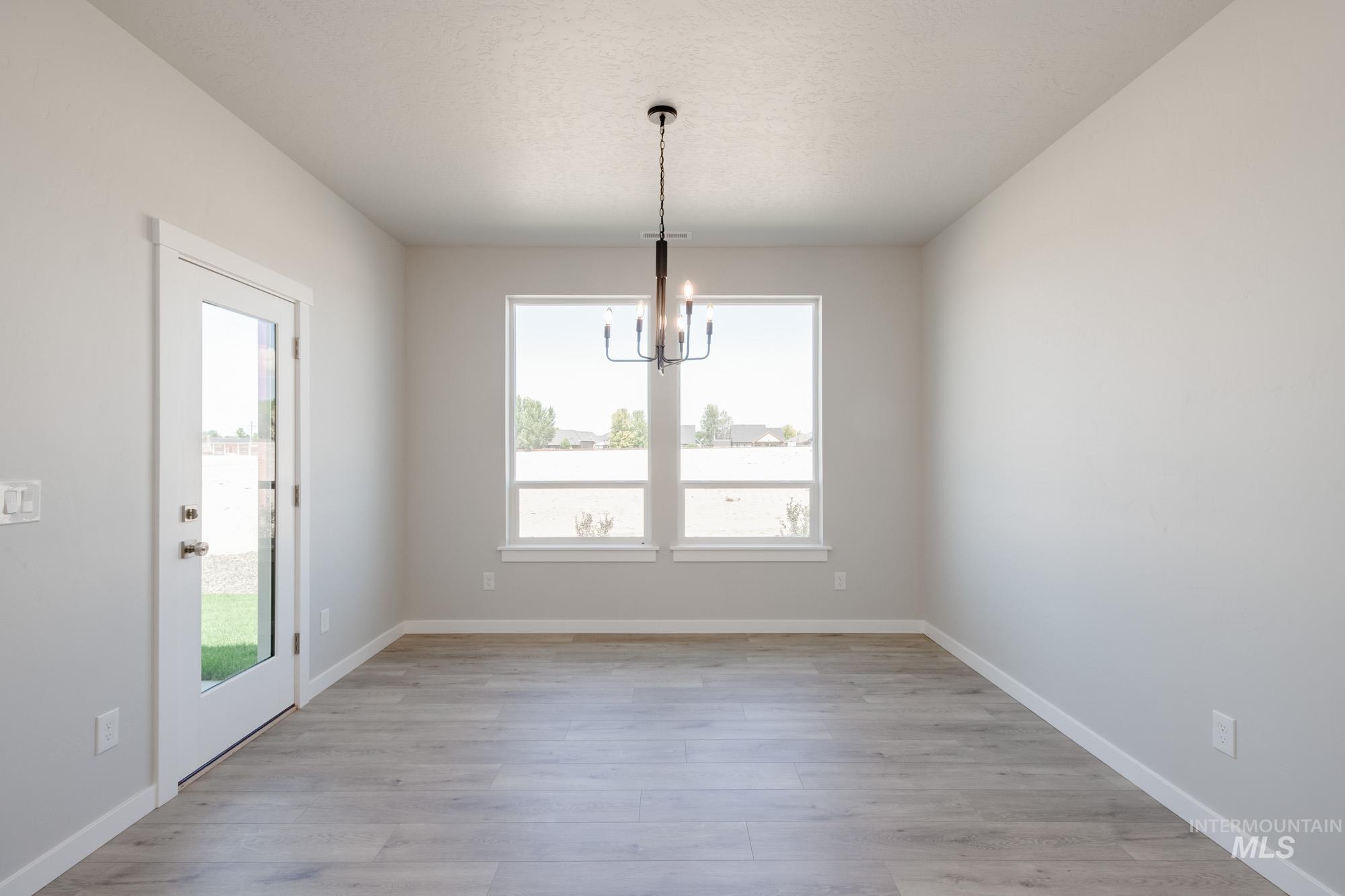 Unfurnished dining area with a chandelier and light wood-style floors