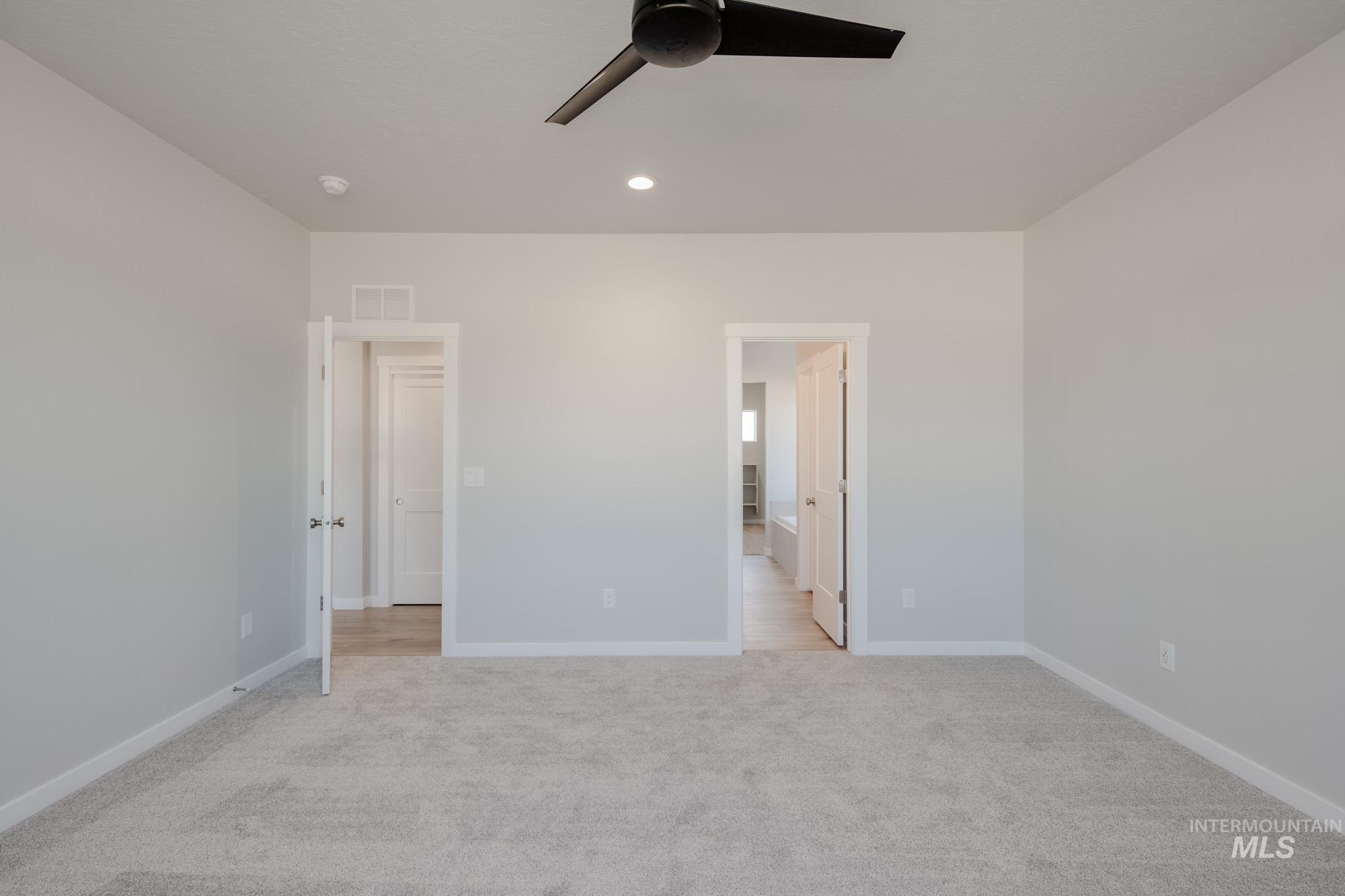 Unfurnished bedroom featuring light colored carpet, recessed lighting, ensuite bath, and ceiling fan